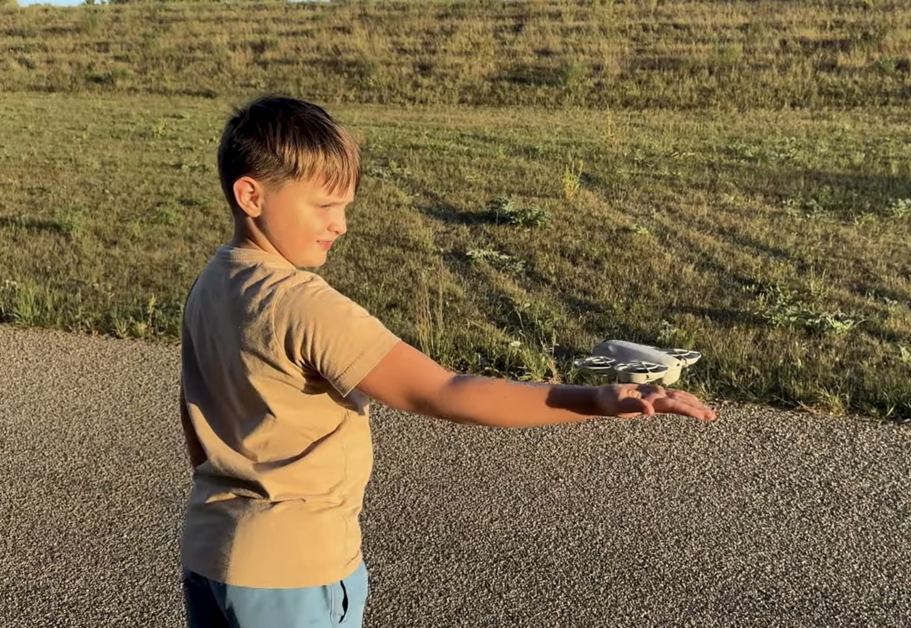 Boy in a tan shirt reaching out to catch the hovering Neo.