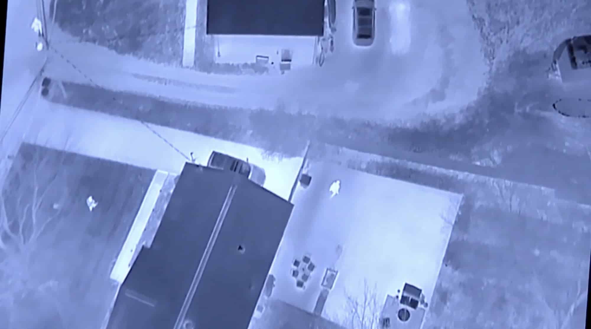Aerial night-vision view of a suburban house and driveway during the midnight manhunt.
