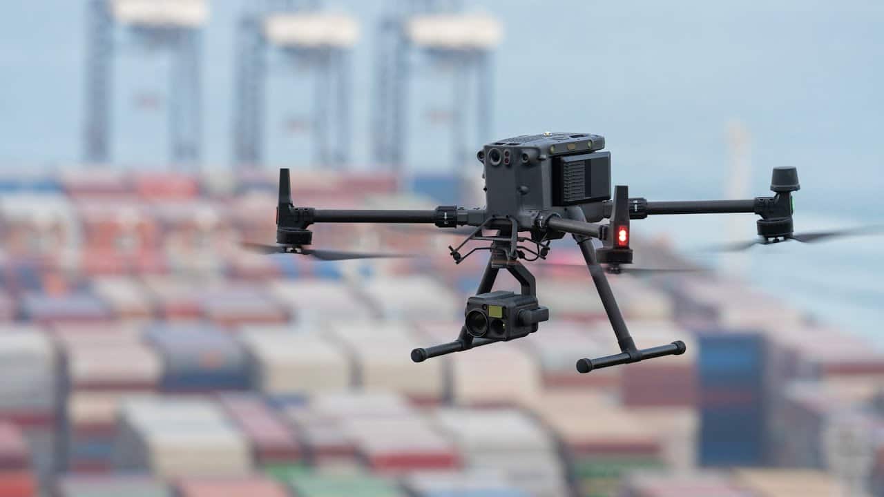 A DJI Matrice 350 RTK hovers above a stacked shipping container yard.