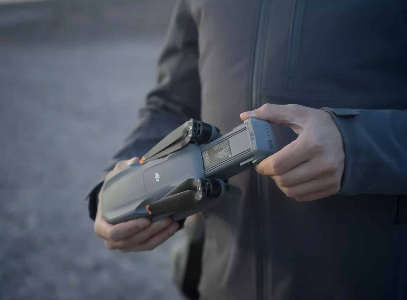 Pilot in a gray jacket cradling the folded Air 3S in both hands.