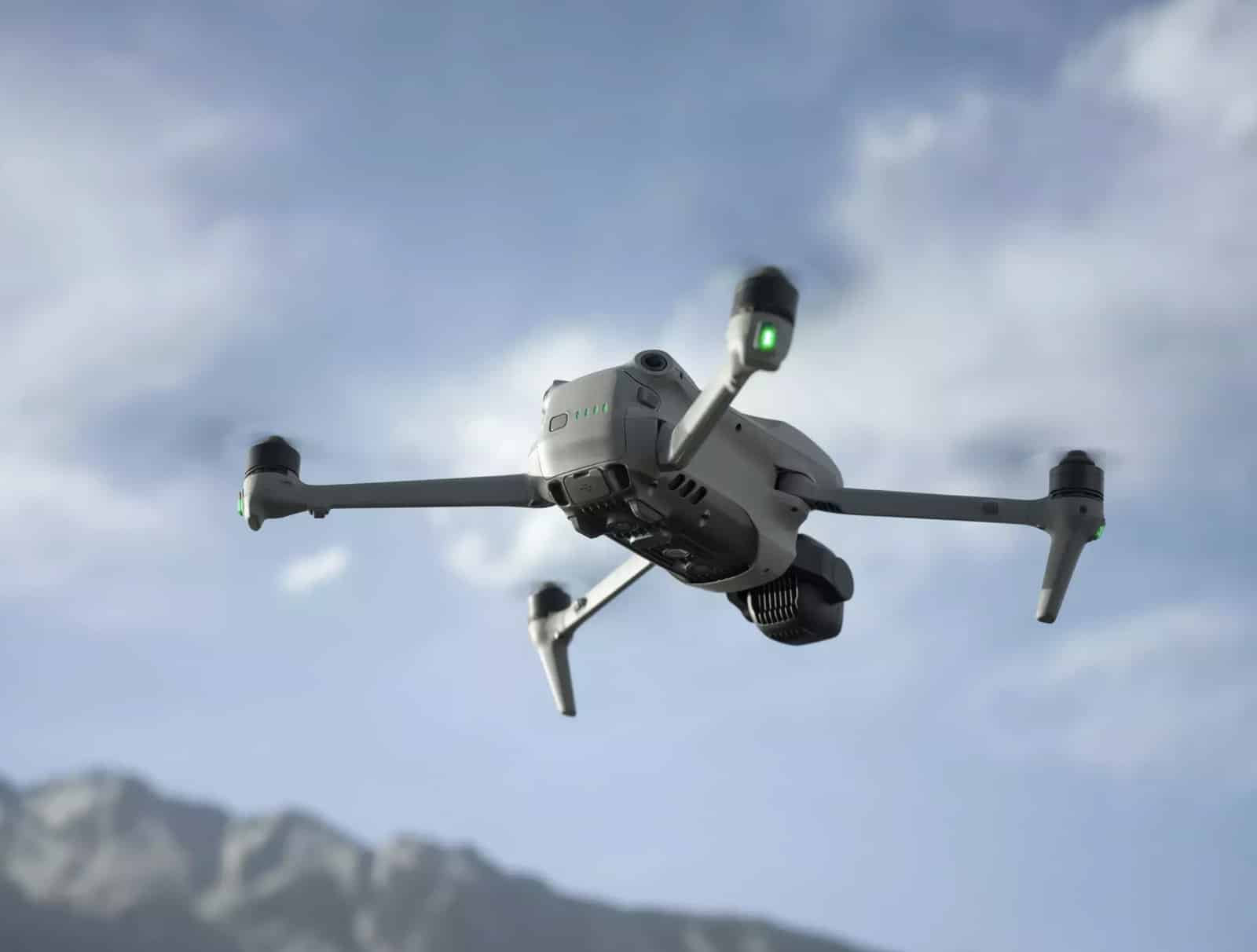 Air 3S climbing against cloud with snow-dusted mountains far below and arms extended.