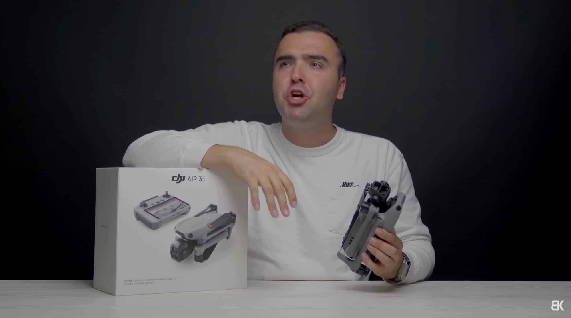 Reviewer holds the DJI Air 3S beside its retail box at a desk.