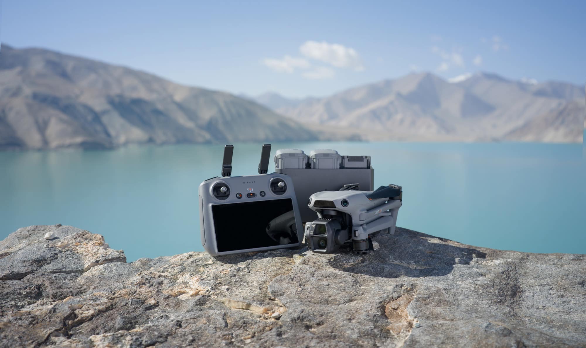 RC 2 controller, charging hub and folded drone lined up on a lakeside rock.