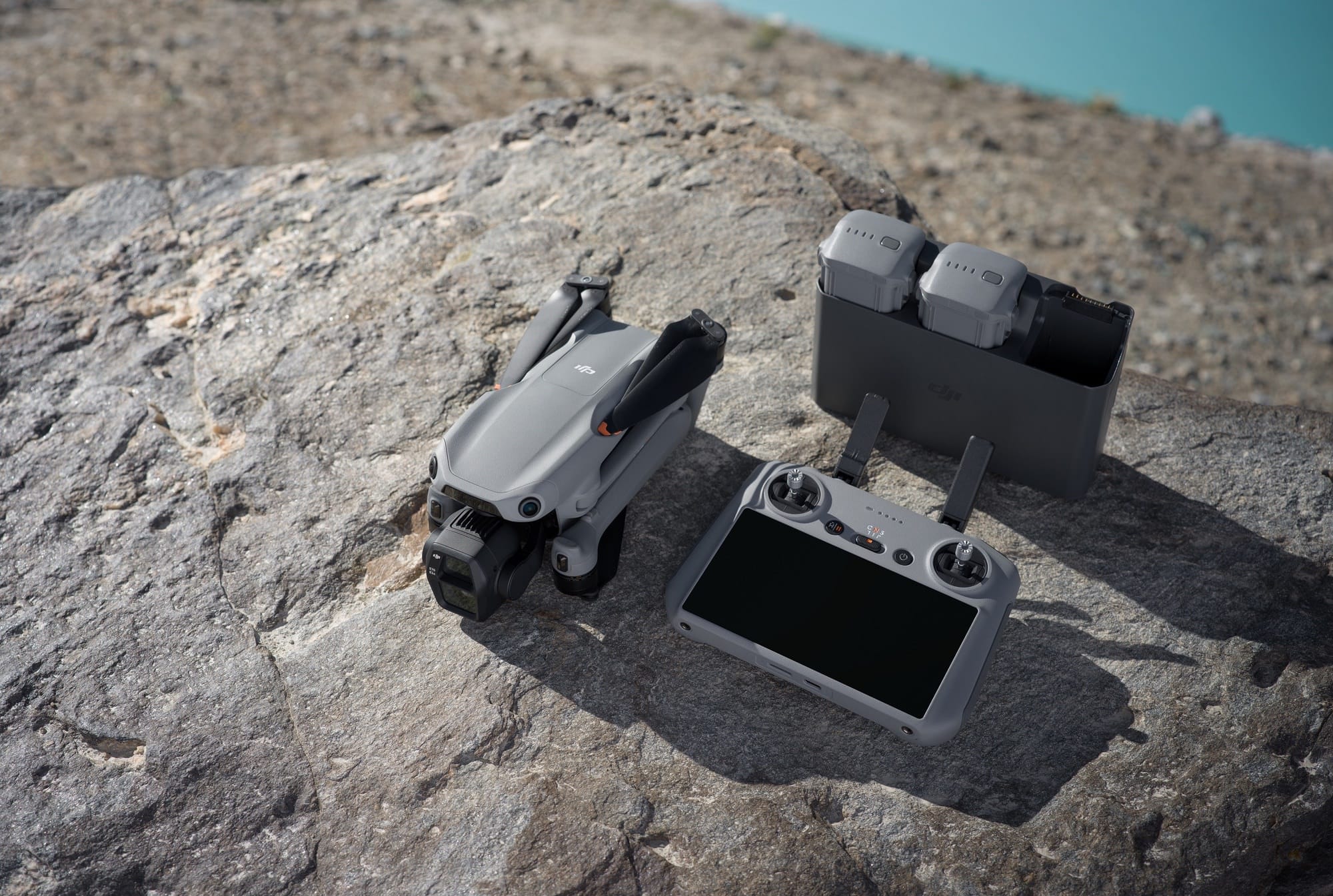 Folded Air 3S, RC 2 controller and a two-battery charging hub on a sunlit boulder.