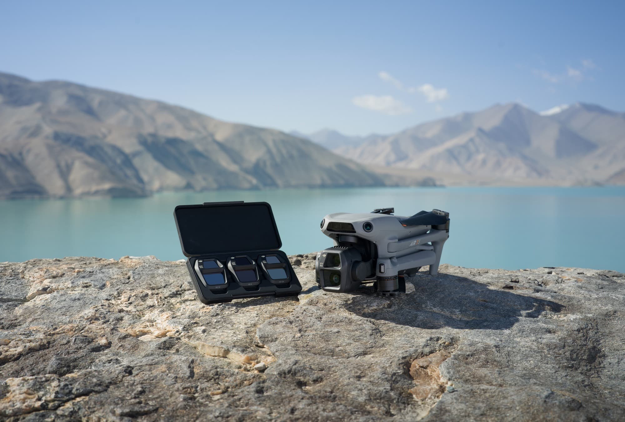 Open filter case holding three ND filters beside the folded drone on rock.