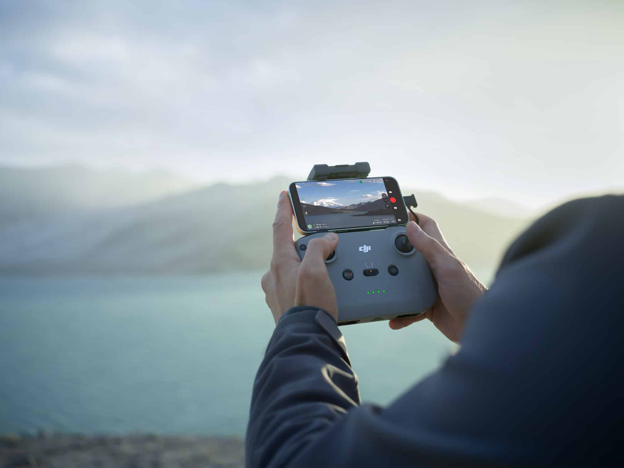 Hands hold an RC-N3 with a phone clamped on top showing the live feed.