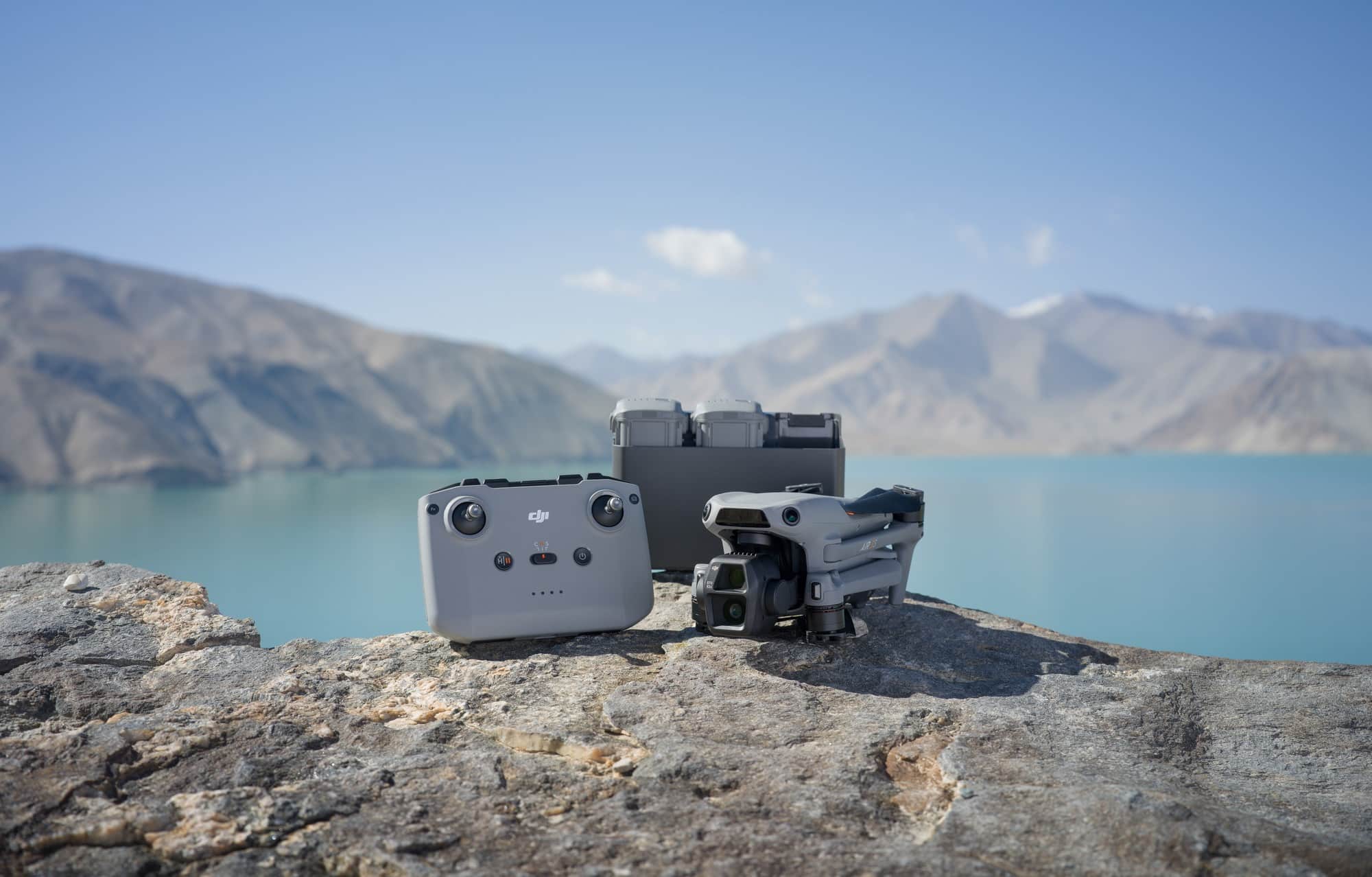 RC-N3 controller, battery hub and folded drone arranged on a lakeside rock.