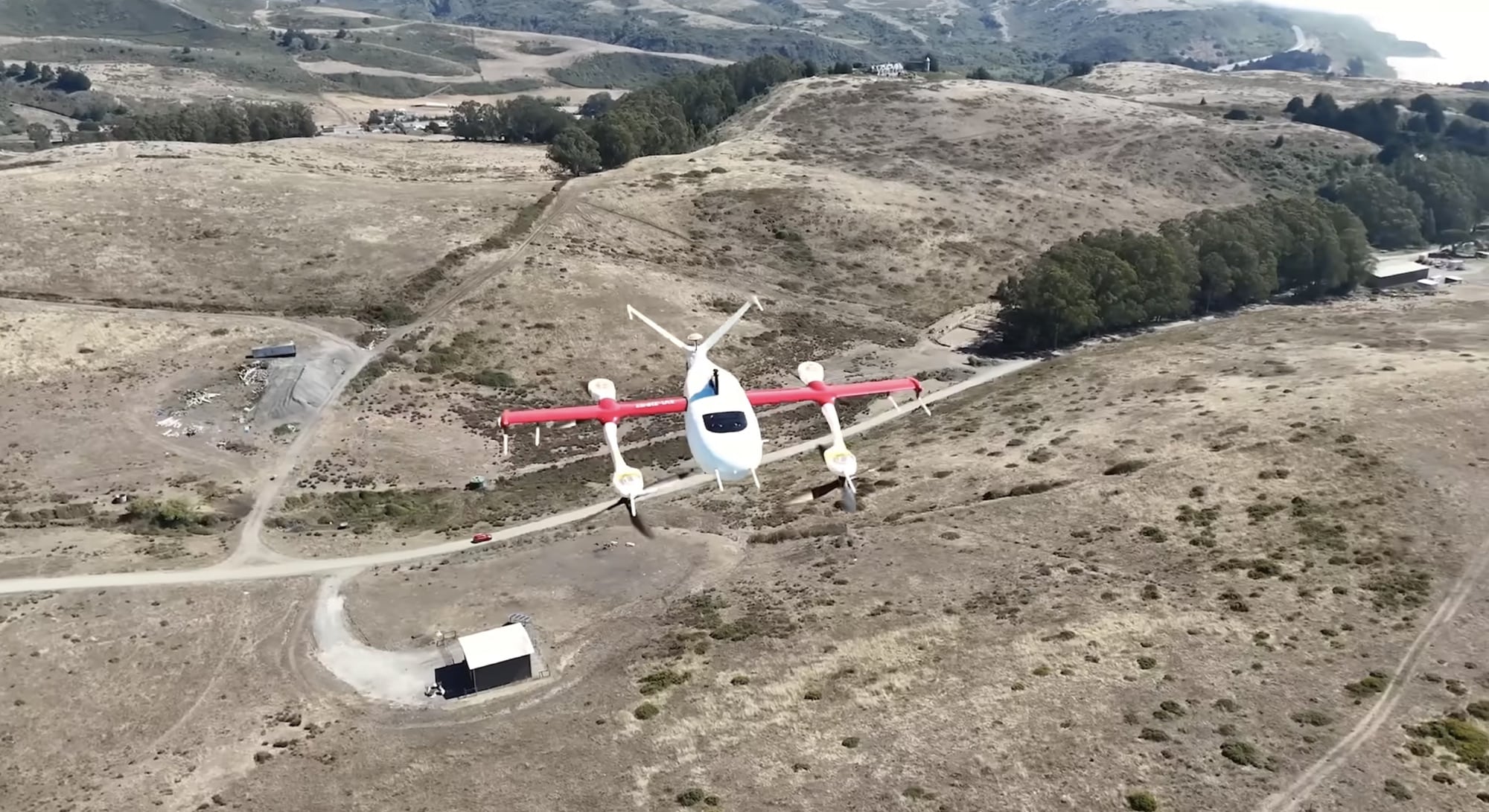 A red-winged Zipline aircraft cruising above golden hills near its test range.