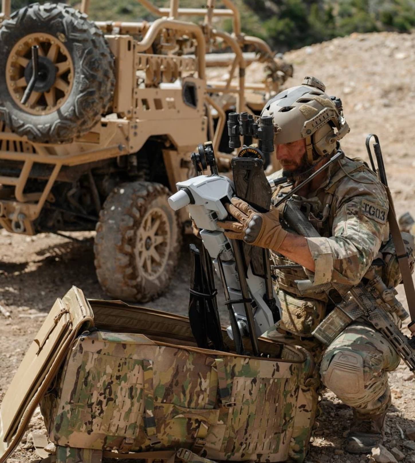 A soldier assembles a Performance Drone Works C-100 from its case beside a tactical vehicle.
