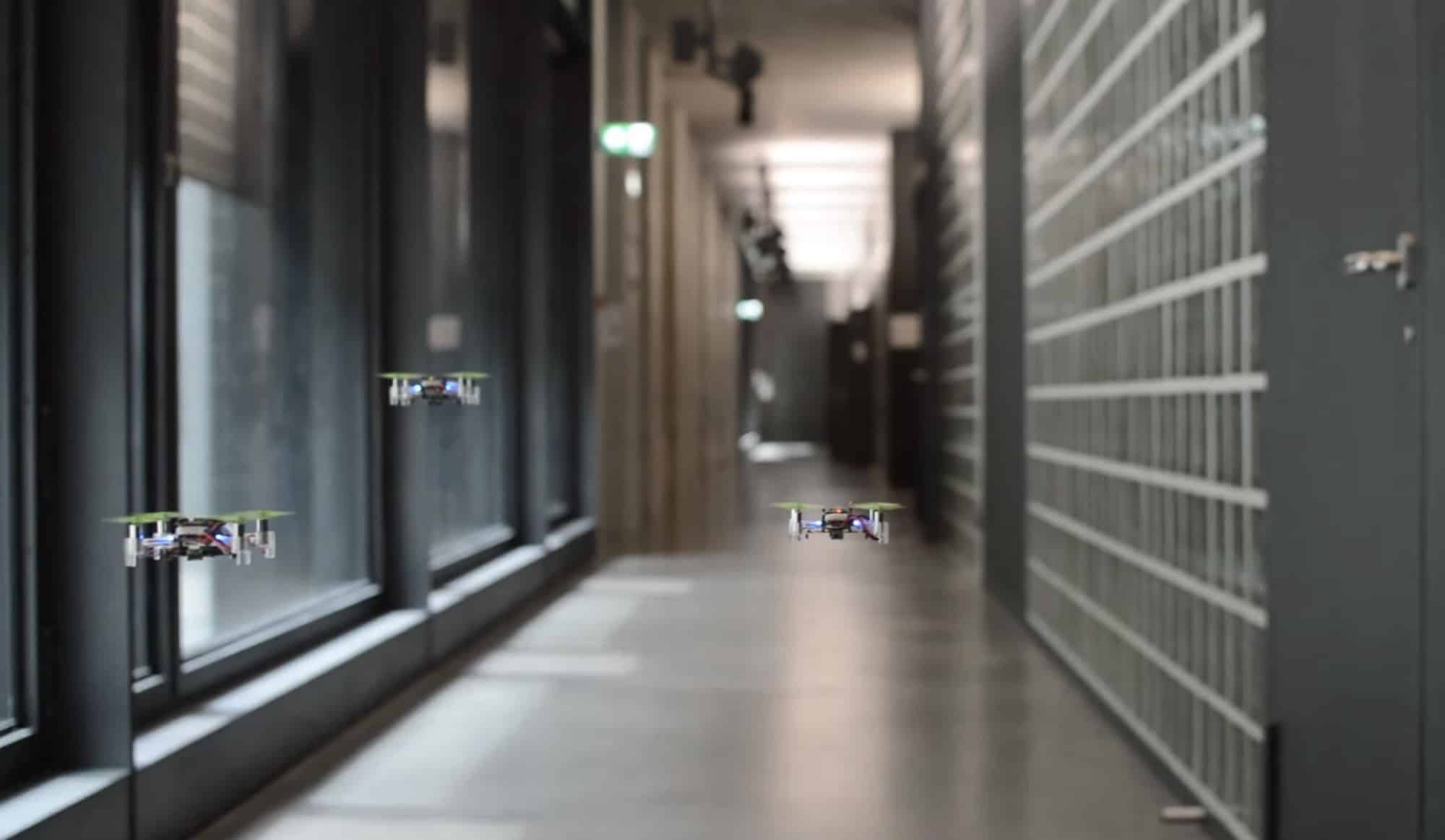 Two tiny drones fly down an office corridor while mapping the space.