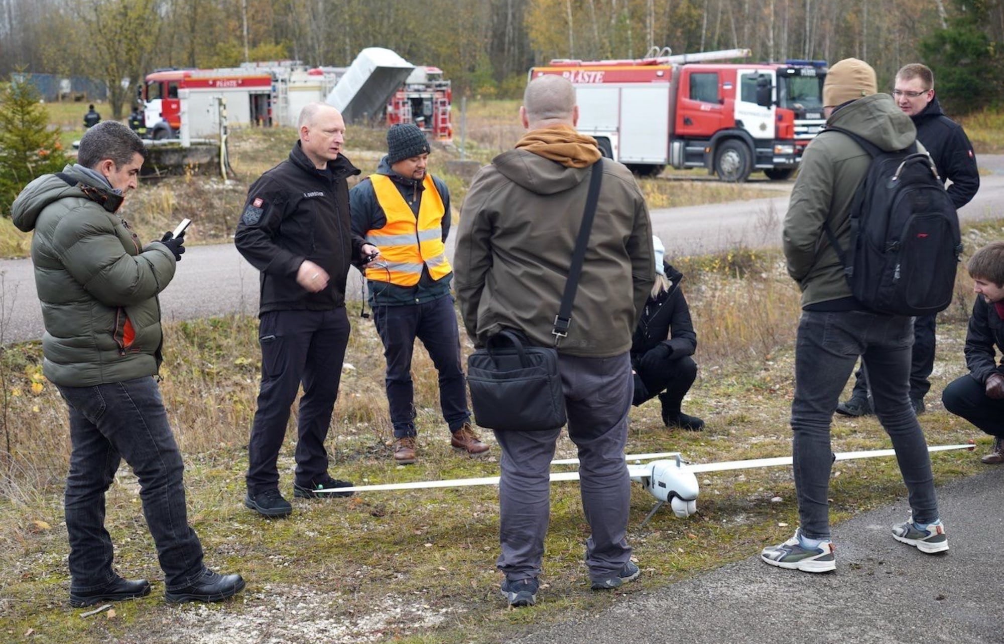 Responders and fire crews gather around a drone during a public safety exercise.