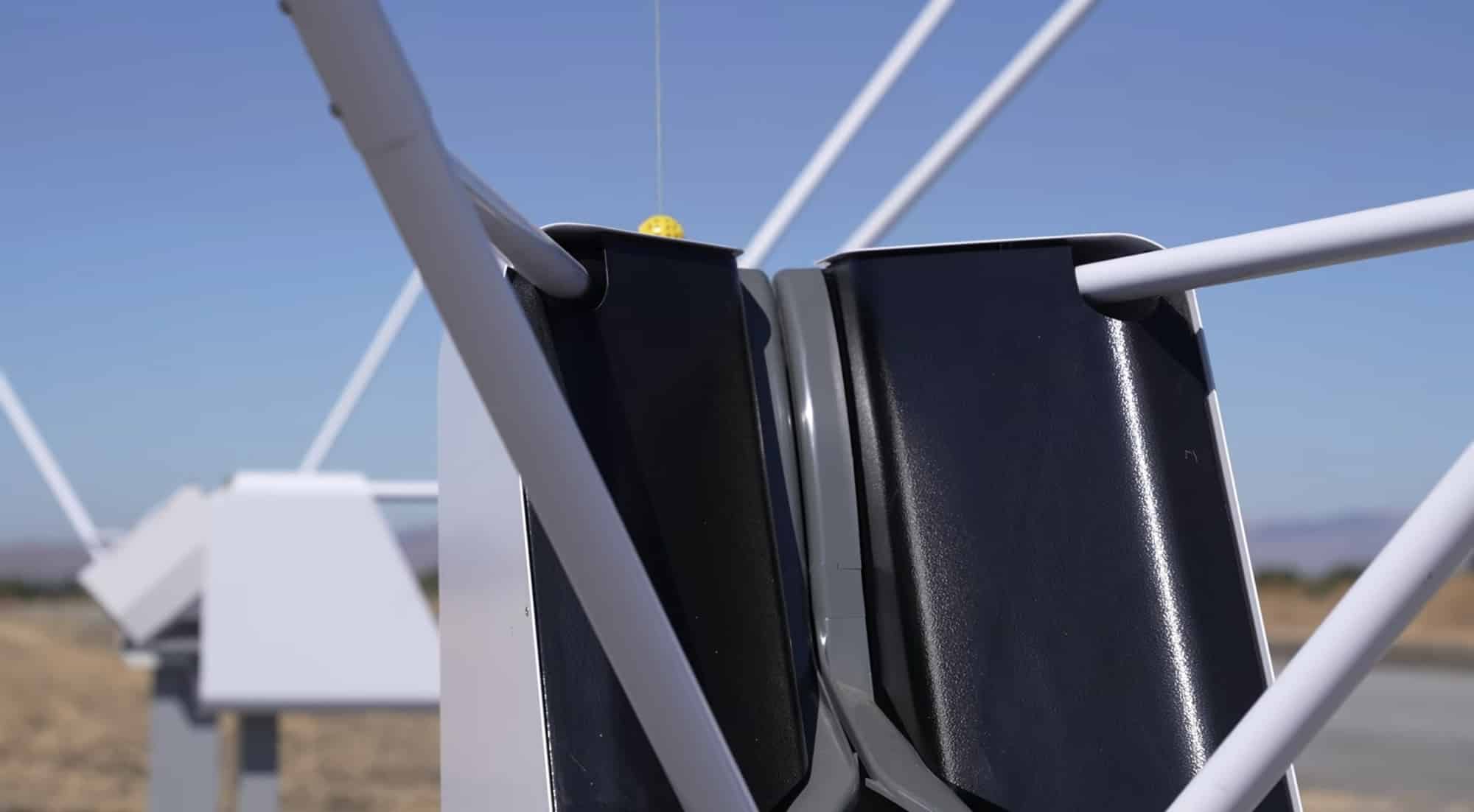 Automated release mechanism letting go of a parcel beneath a hovering Wing aircraft.