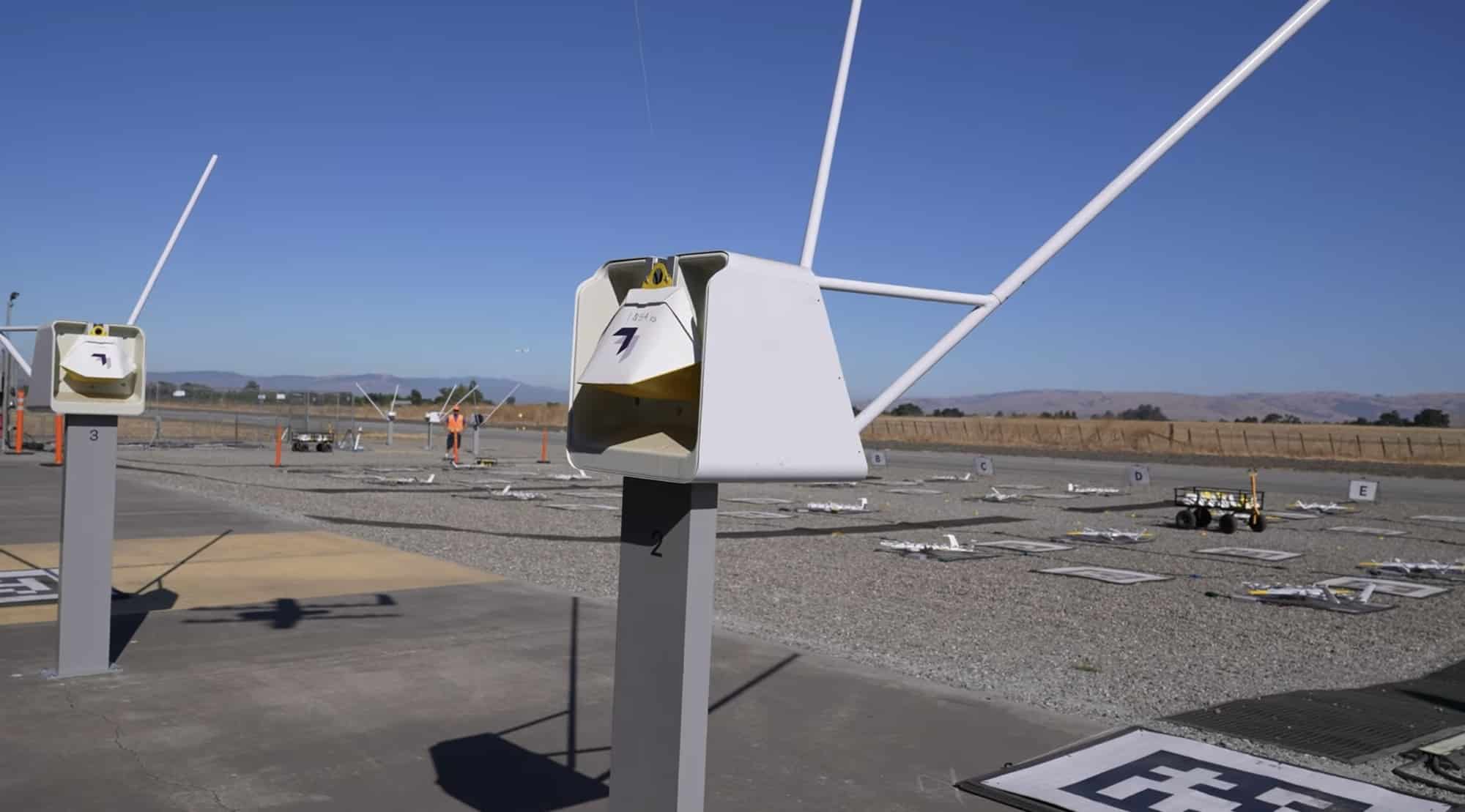Wing aircraft lowering a package on its tether during delivery security testing.