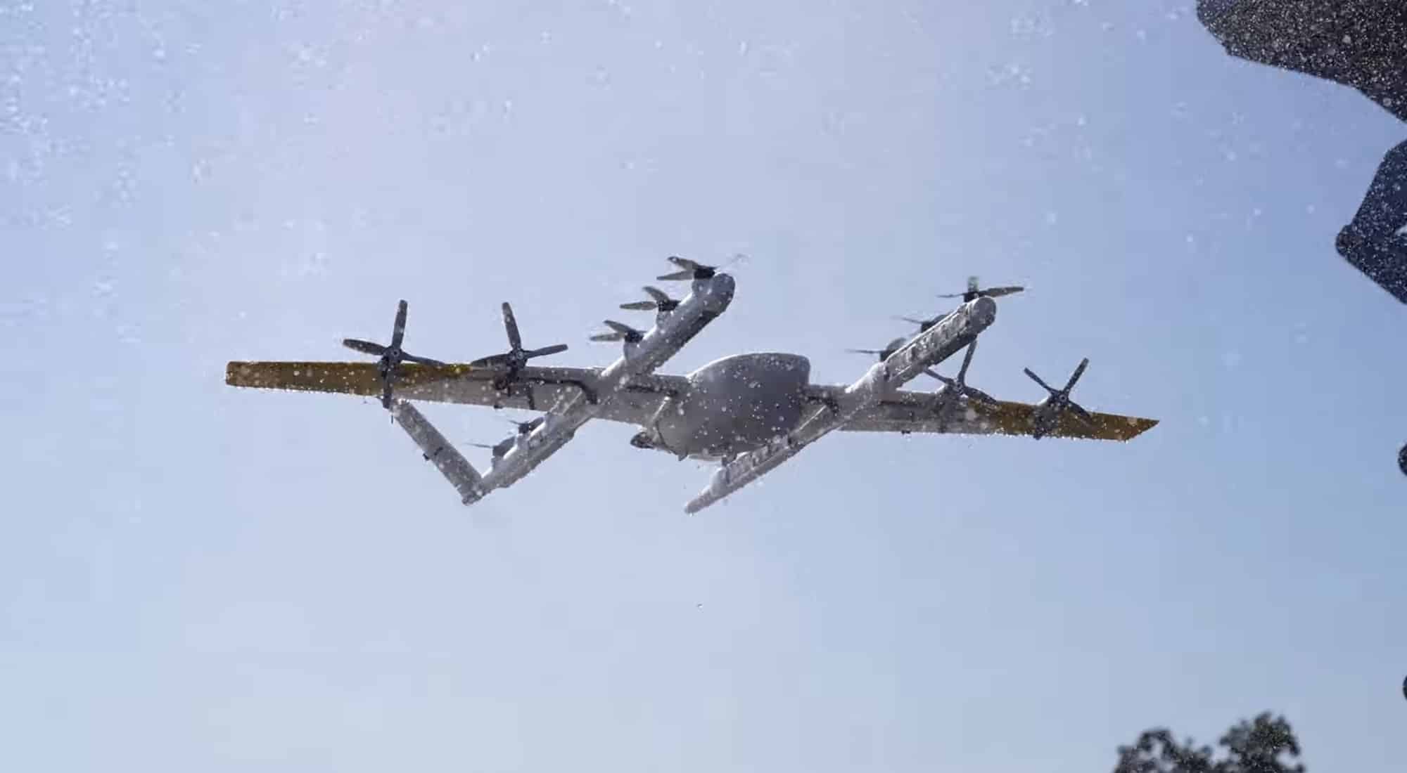 Tan Wing delivery aircraft with multiple lift rotors flying through falling snow.