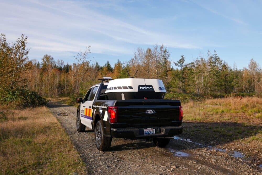 Police pickup carrying a white BRINC drone nest parked on a gravel track.
