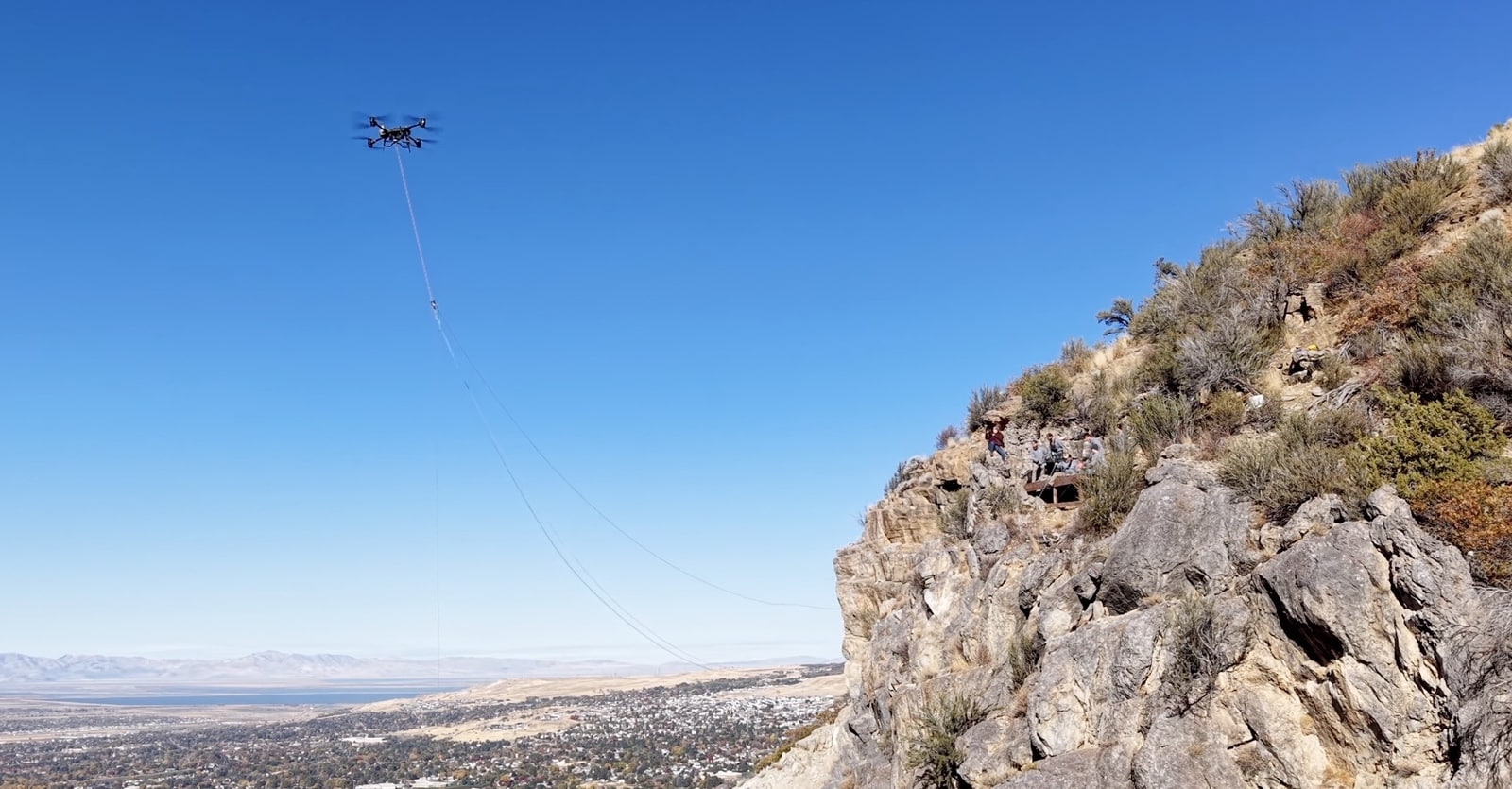 FlyCart 30 high above the Ogden valley trailing rope lines toward a cliff.