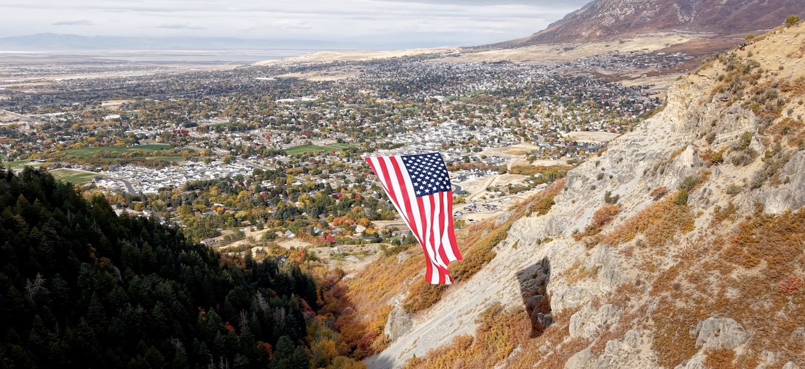 Flag suspended over the canyon with Ogden and the valley floor beyond.