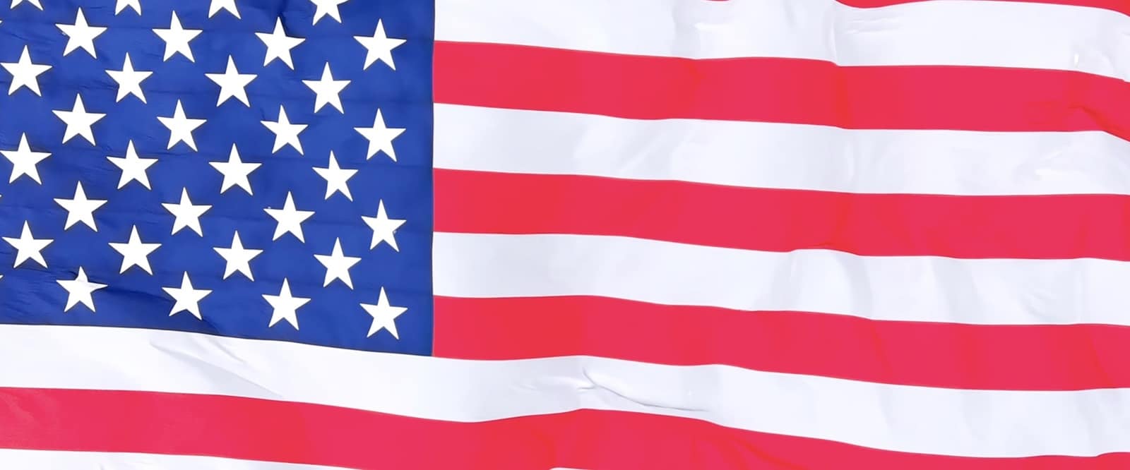 Close aerial detail of the flag's stars and stripes rippling in the wind.