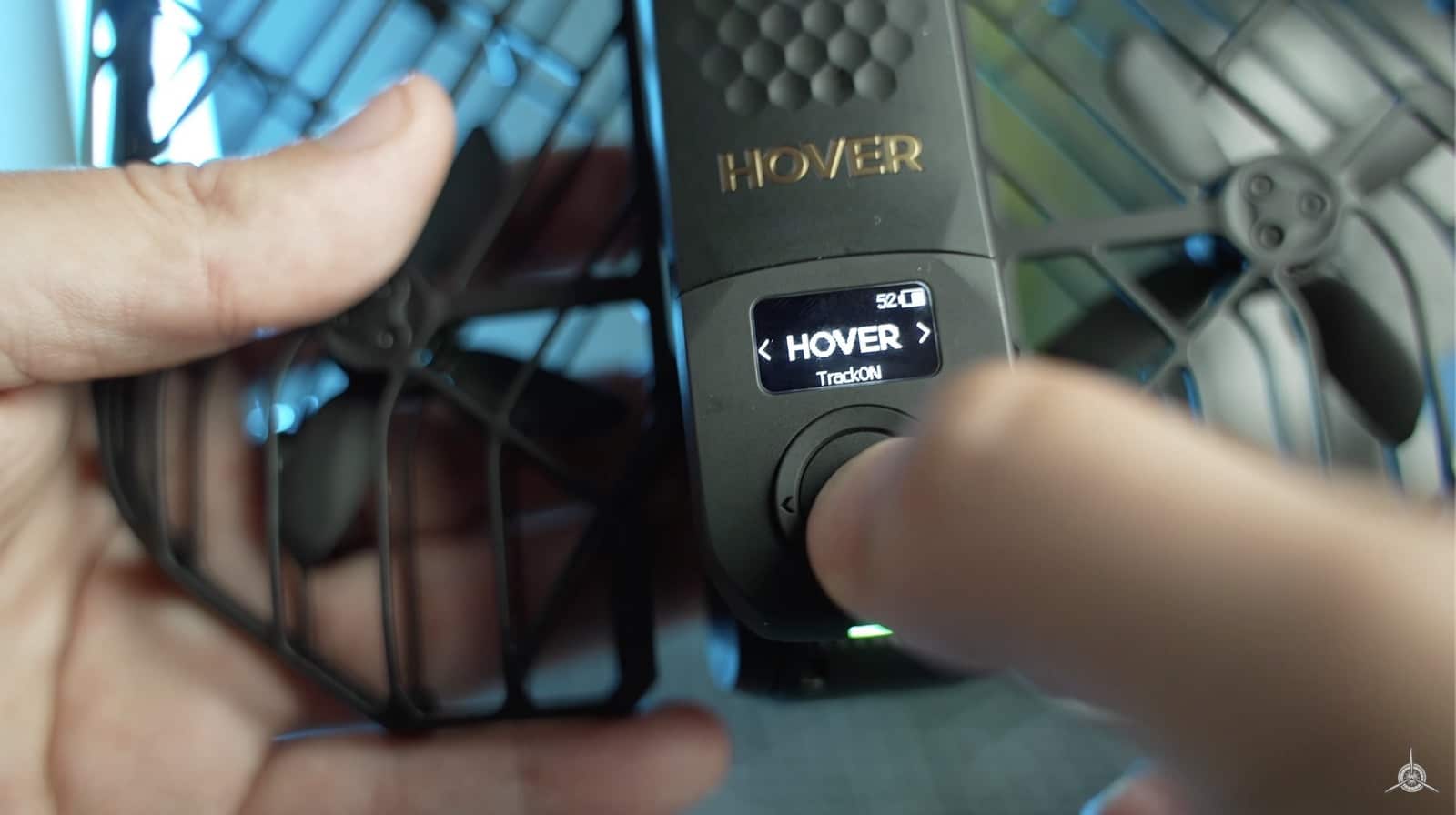 Thumb pressing the mode dial on the HoverAir X1 ProMax beside its folded rotors.
