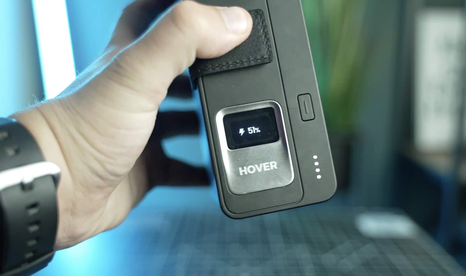 Hand holding the HoverAir charging case with its display reading 5 percent.