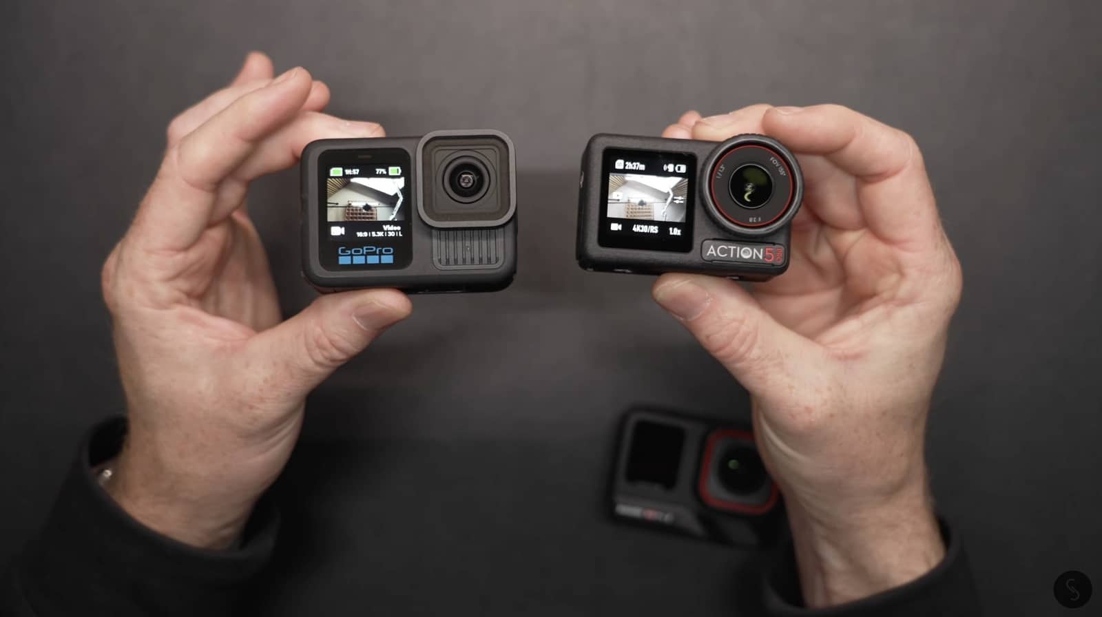 Hands holding a GoPro Hero 13 Black and a DJI Osmo Action 5 Pro.