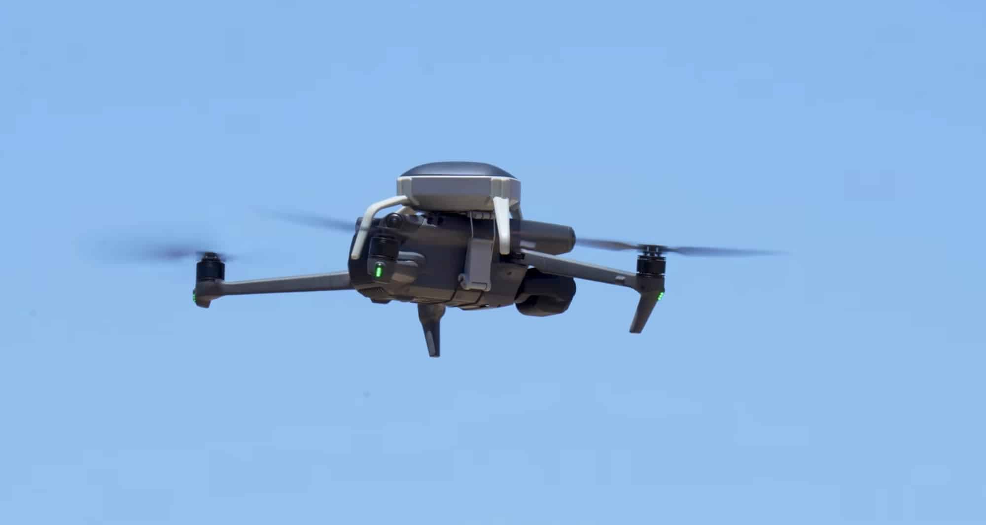 Drone fitted with a ParaZero parachute canister flying against a blue sky.