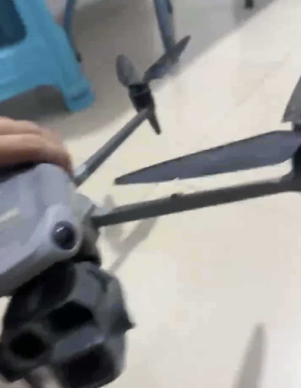 A hand lifts the prototype, its propellers bent from an apparent crash test.