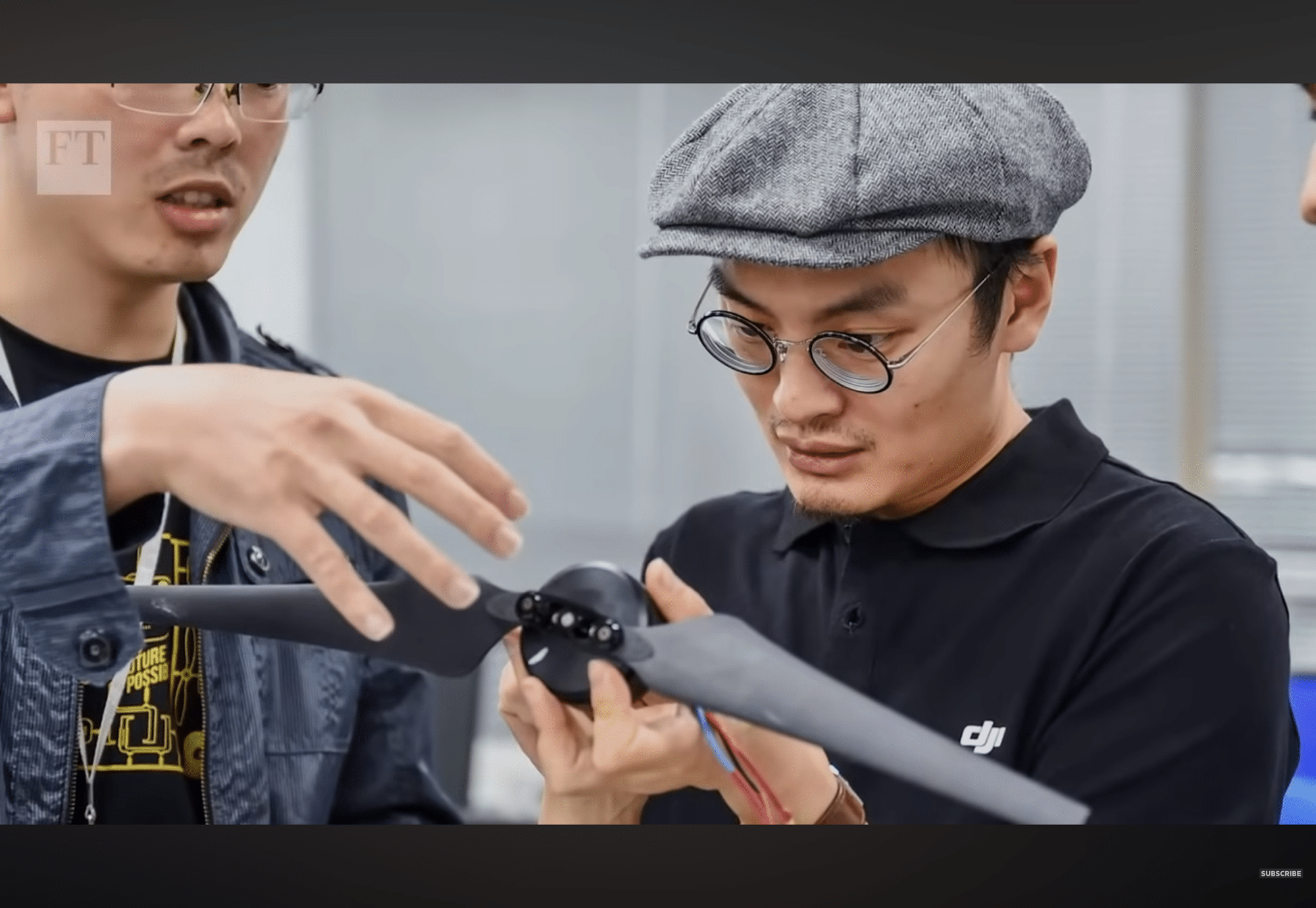 Documentary still of DJI founder Frank Wang examining a drone arm and propeller.