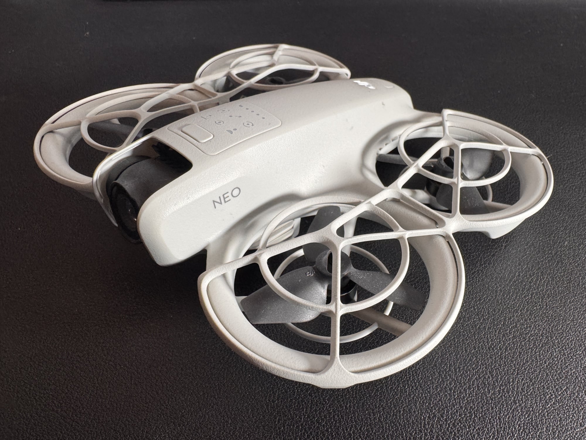 DJI Neo with its ducted propeller guards resting on a dark surface.