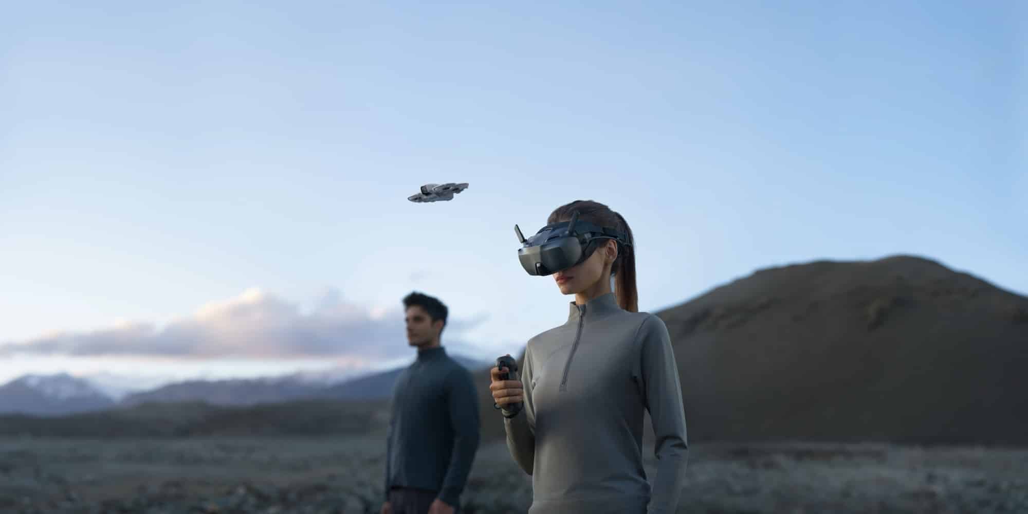 Woman wearing the Goggles N3 flies a DJI Neo beside a mountain lake at dusk.
