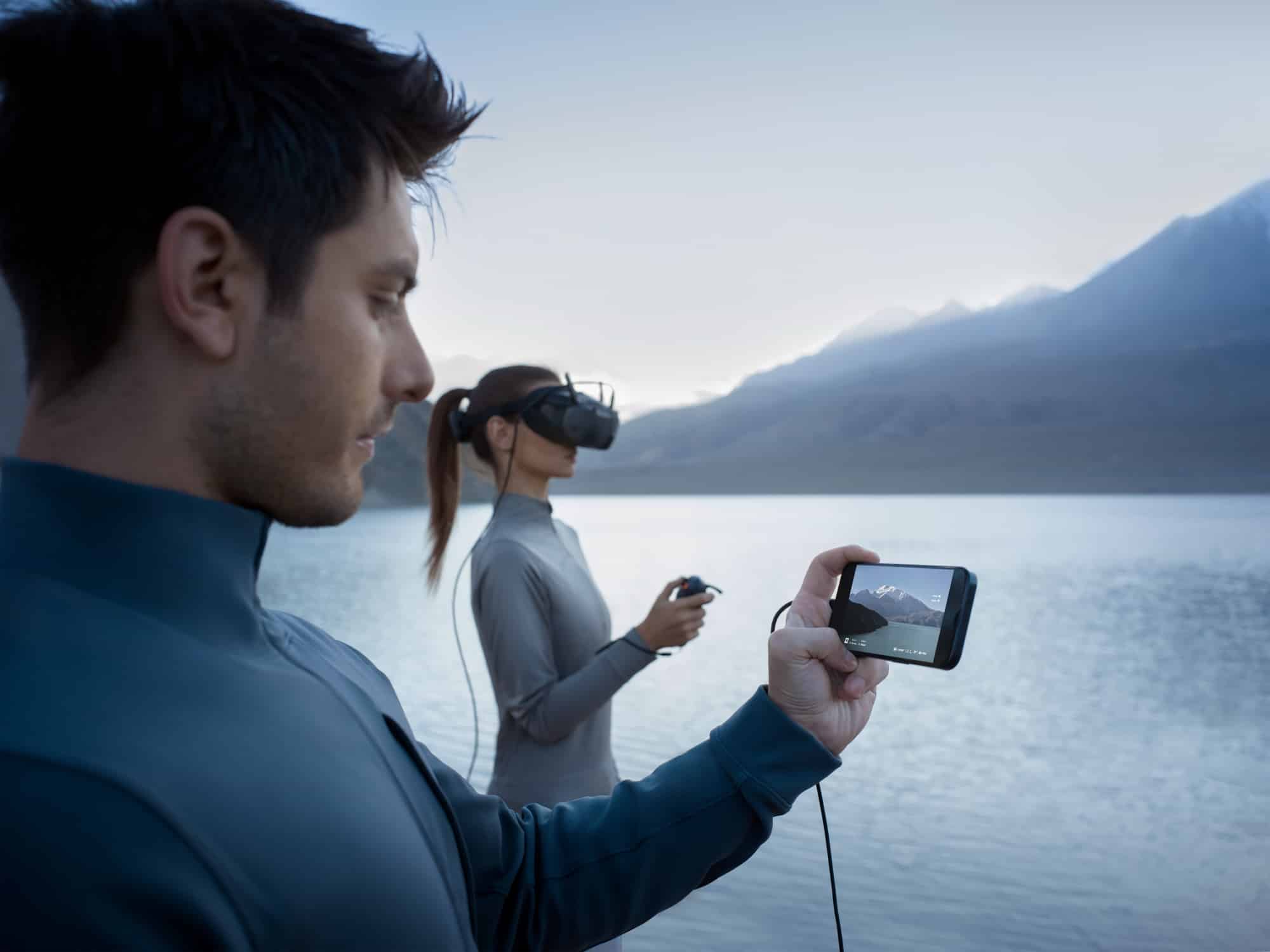 Pilot holding a smartphone that mirrors the live feed from a partner's goggles.