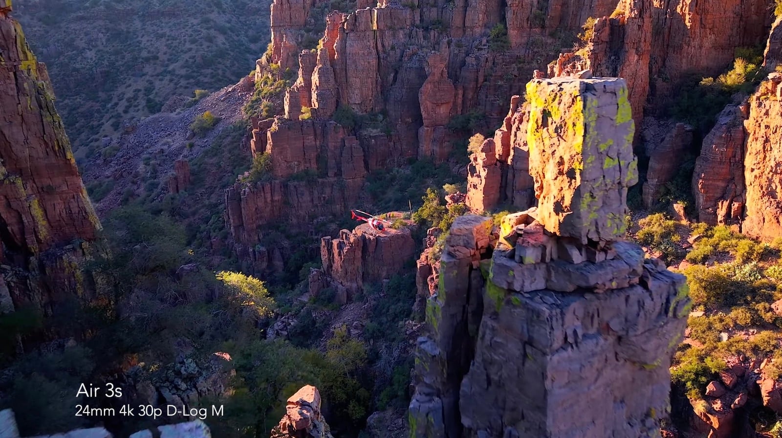 Air 3S sample frame of sunlit red rock spires in a desert canyon.