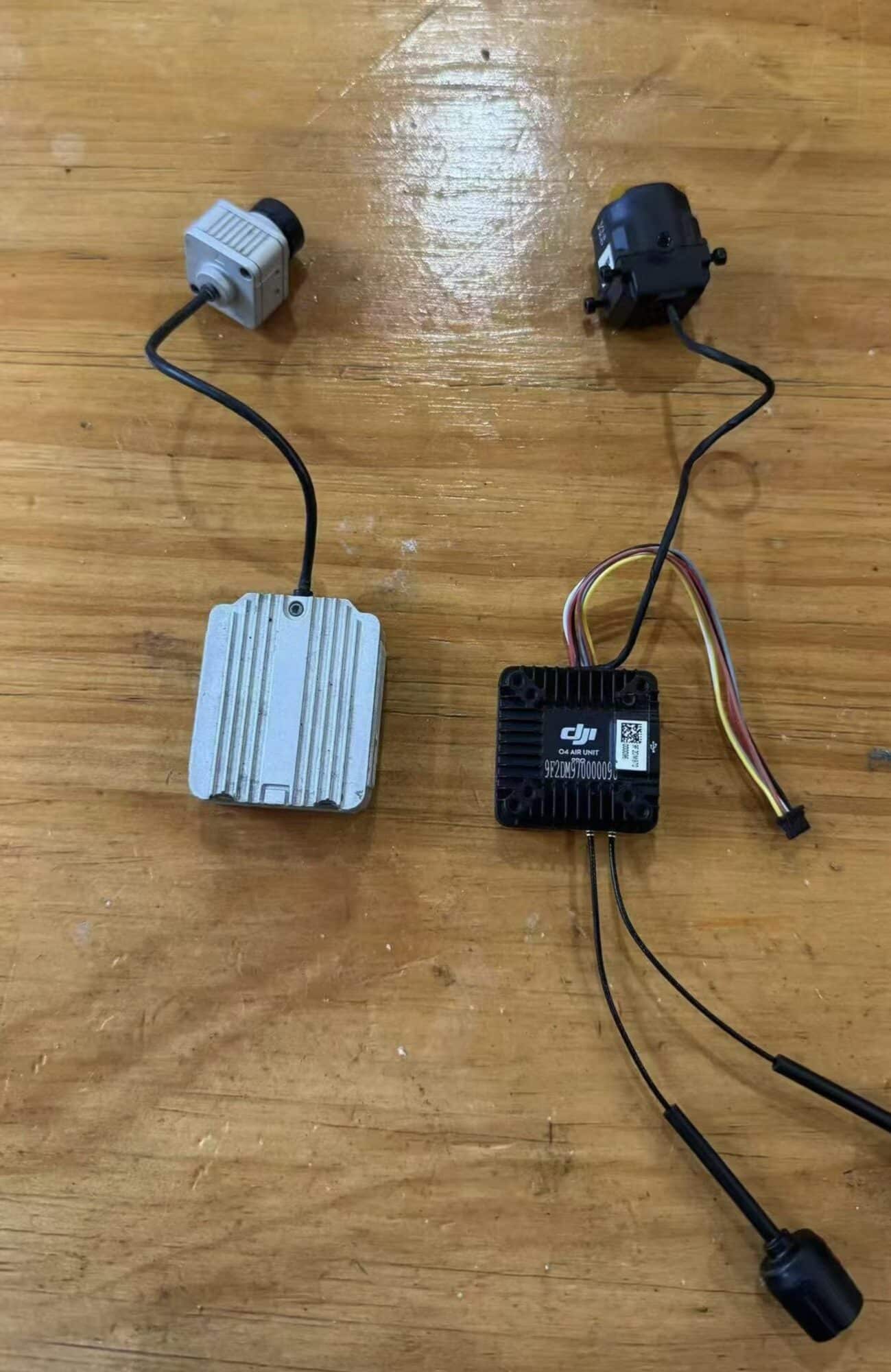 Two leaked DJI FPV air unit modules with cameras and cabling on wood.