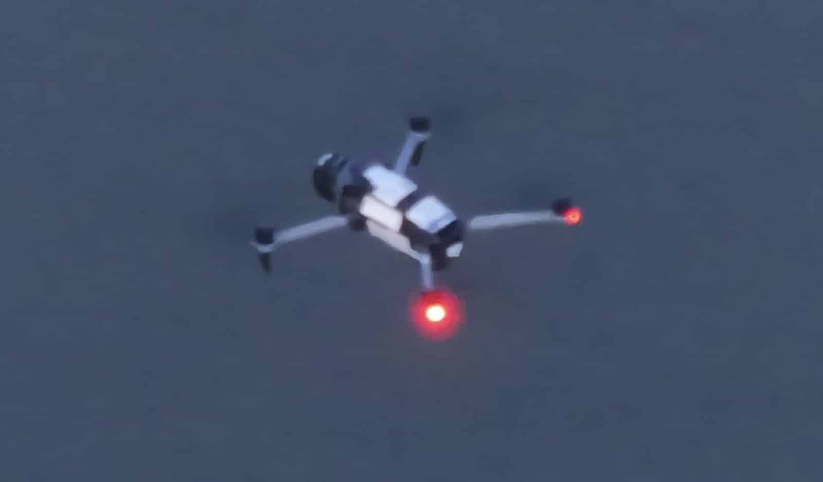 A DJI test pilot crouched beside a Mavic 4 Pro prototype covered in testing stickers.