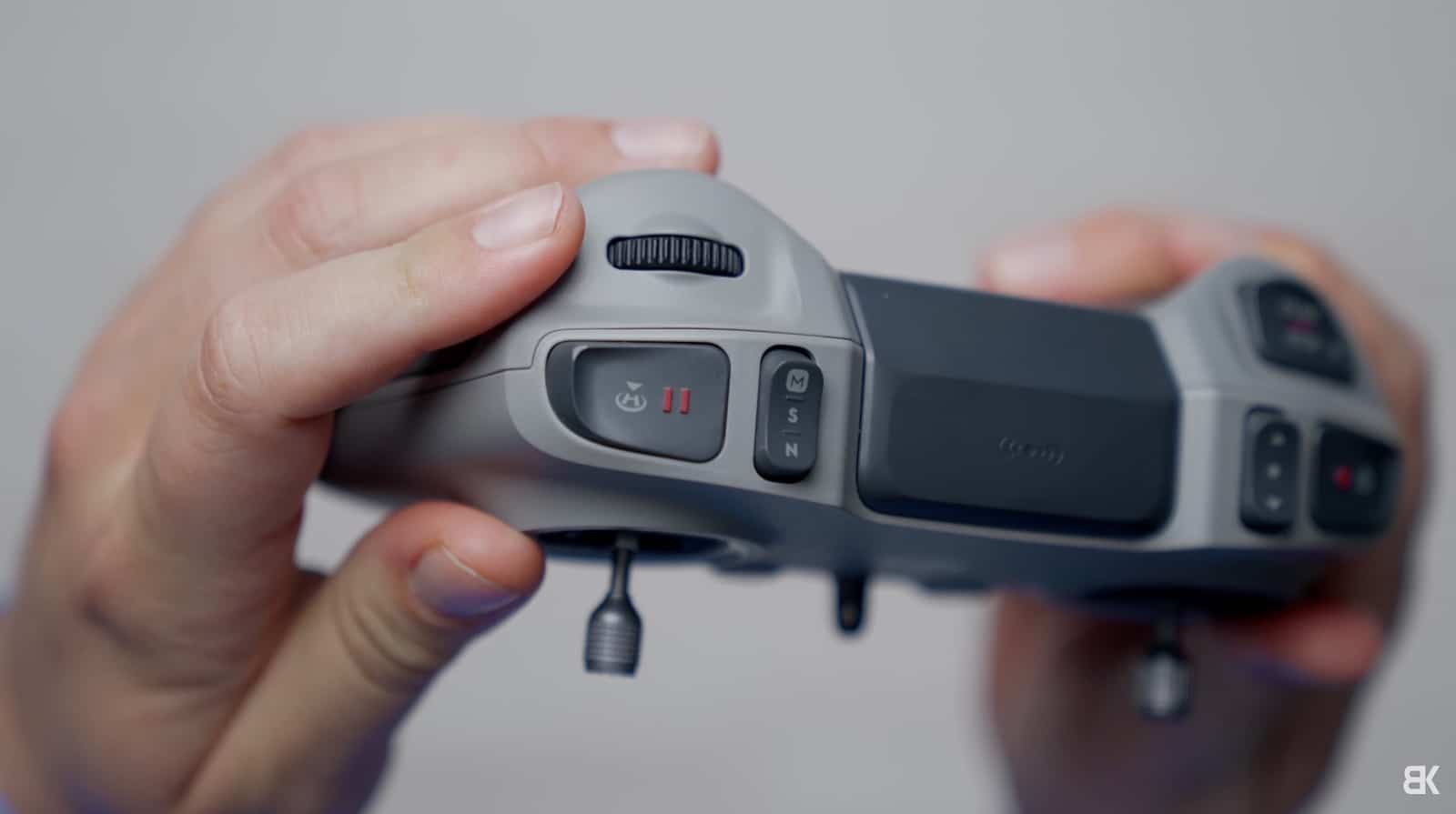 Hands gripping the DJI FPV Remote Controller 3 against a plain background.