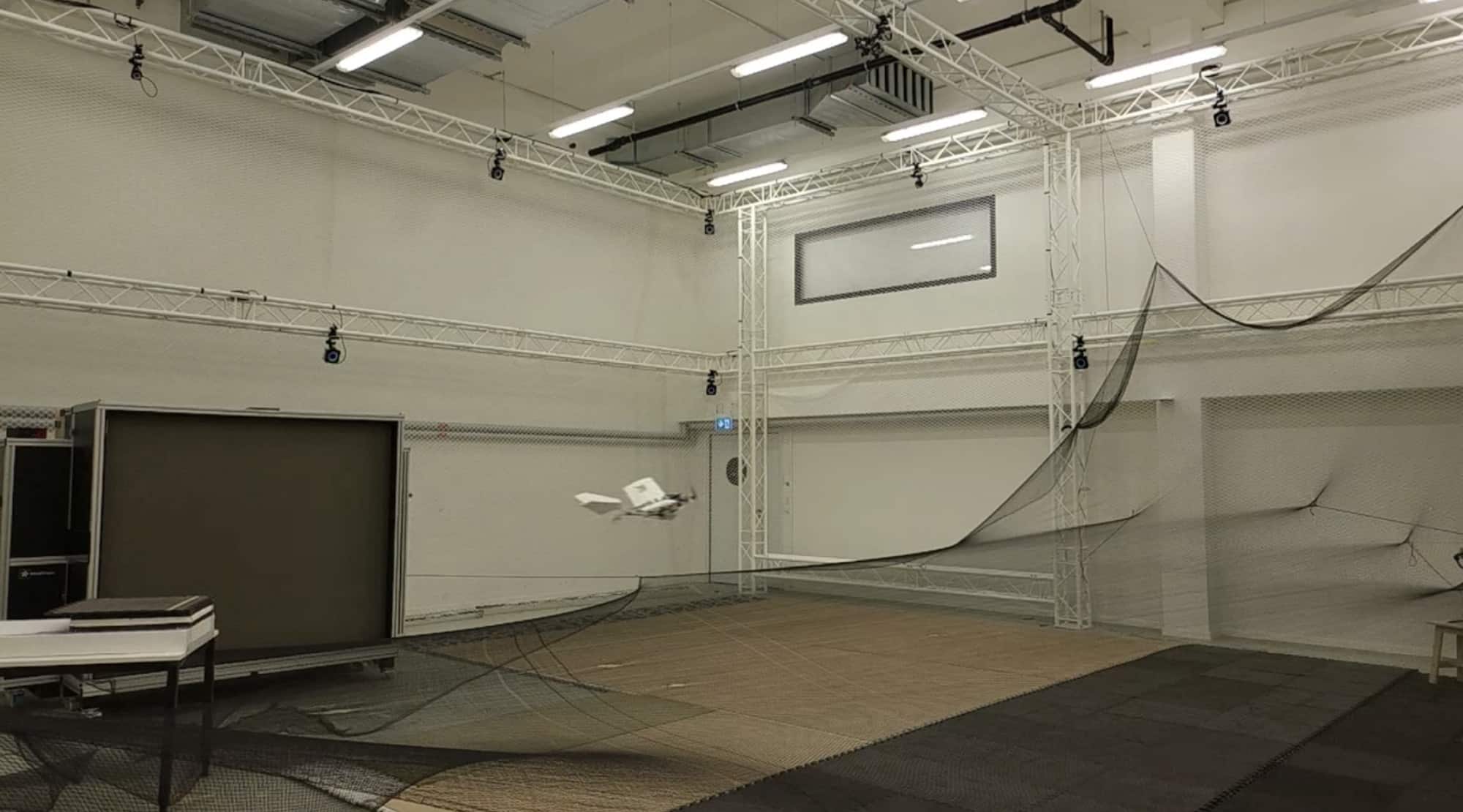 The legged research drone gliding low across the same laboratory floor.