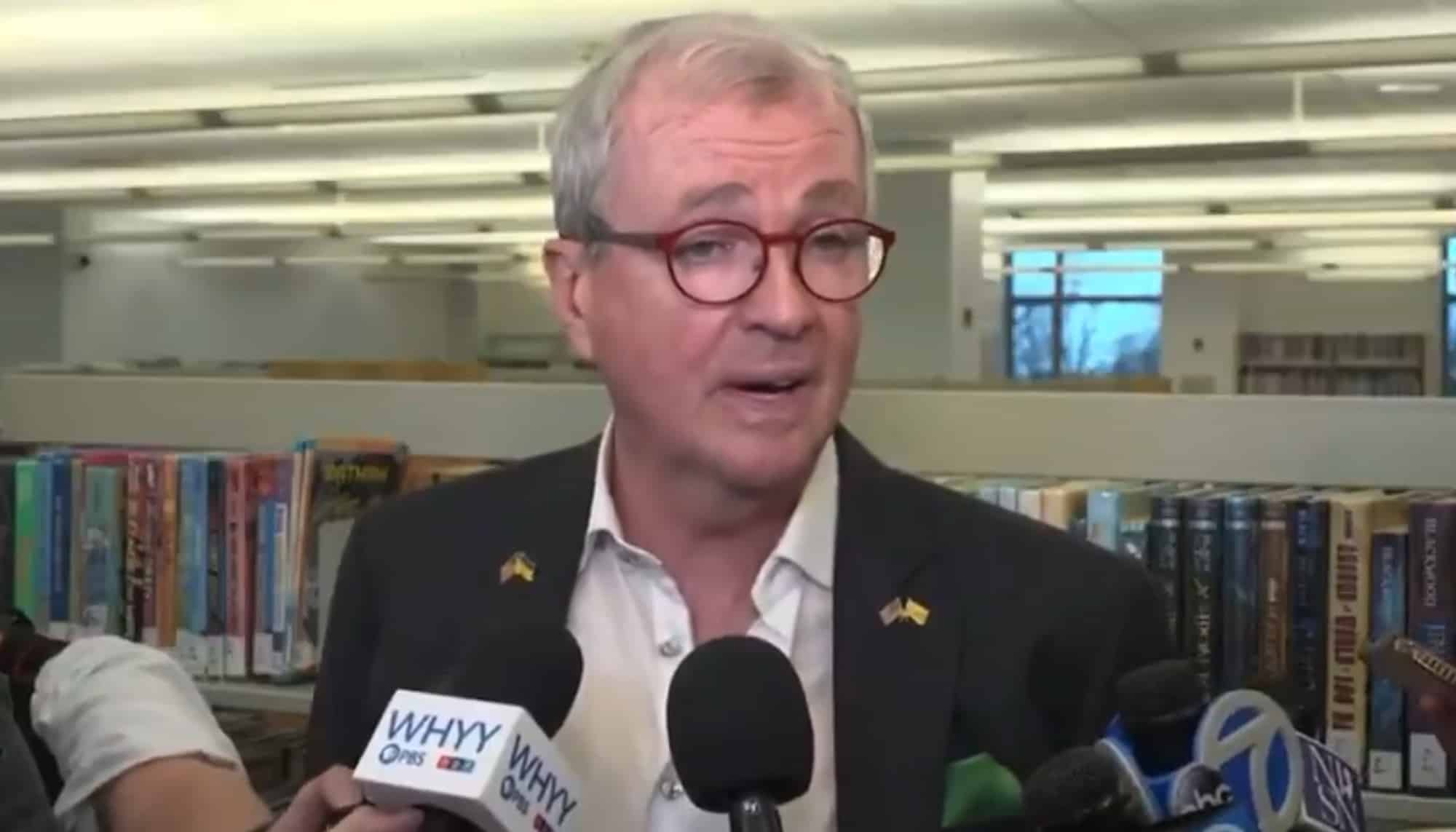 New Jersey's governor answering reporters at a press gaggle in a library.