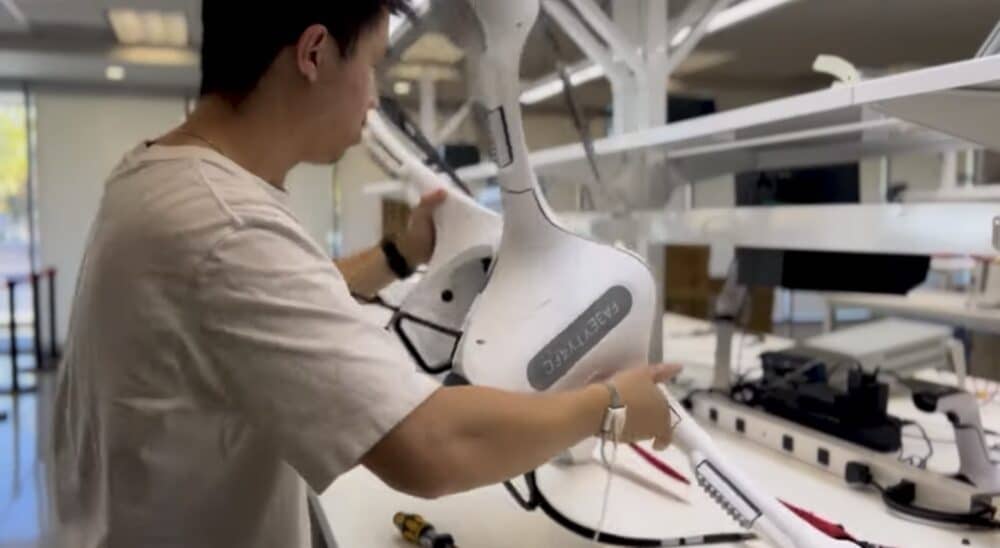 Technician assembles a white Matternet airframe at a workbench in the company workshop.