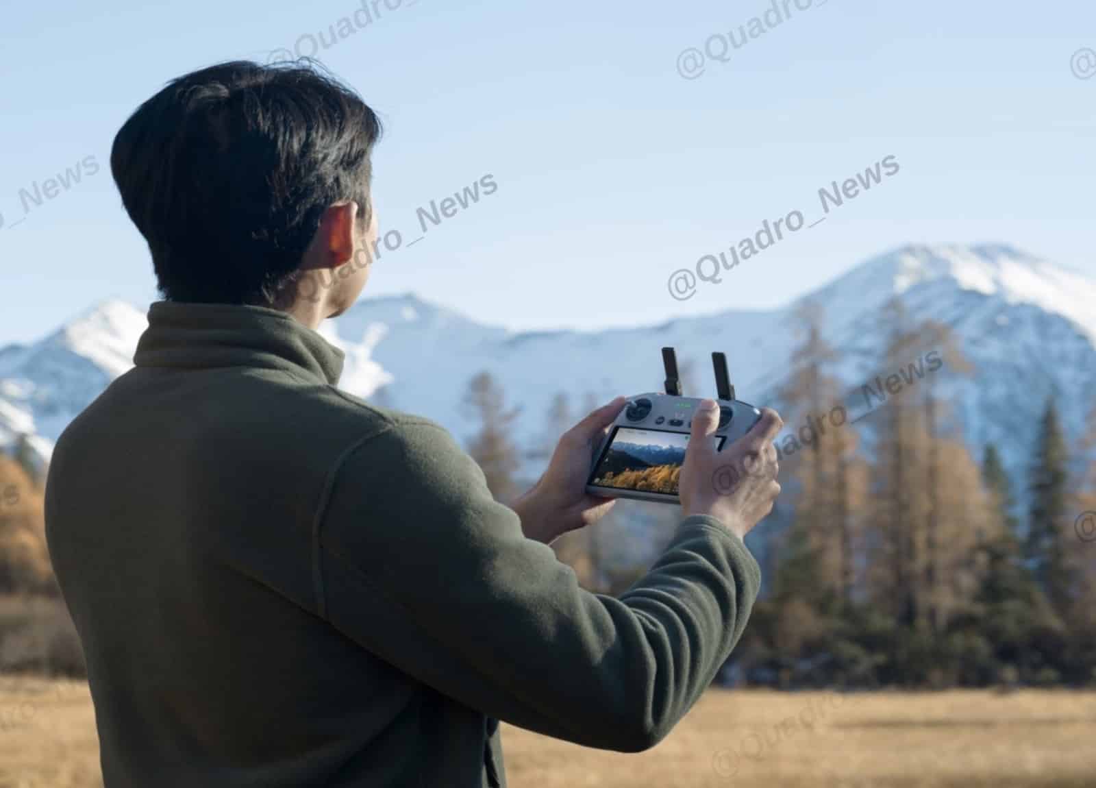 Man in a green fleece flying with a DJI RC 2 before snowy mountains.