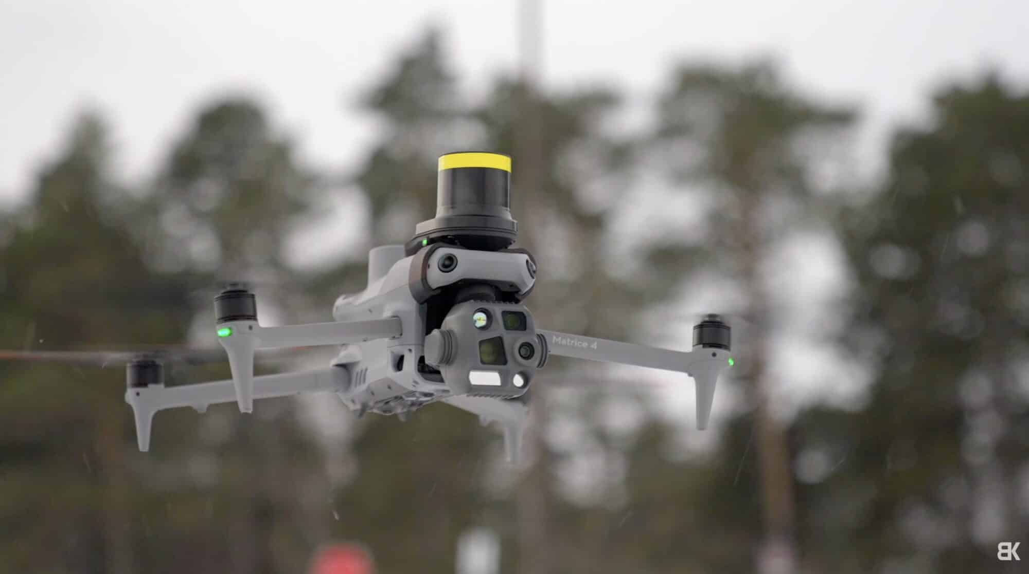 Matrice 4T hovering against bare winter trees with its laser rangefinder turret on top.
