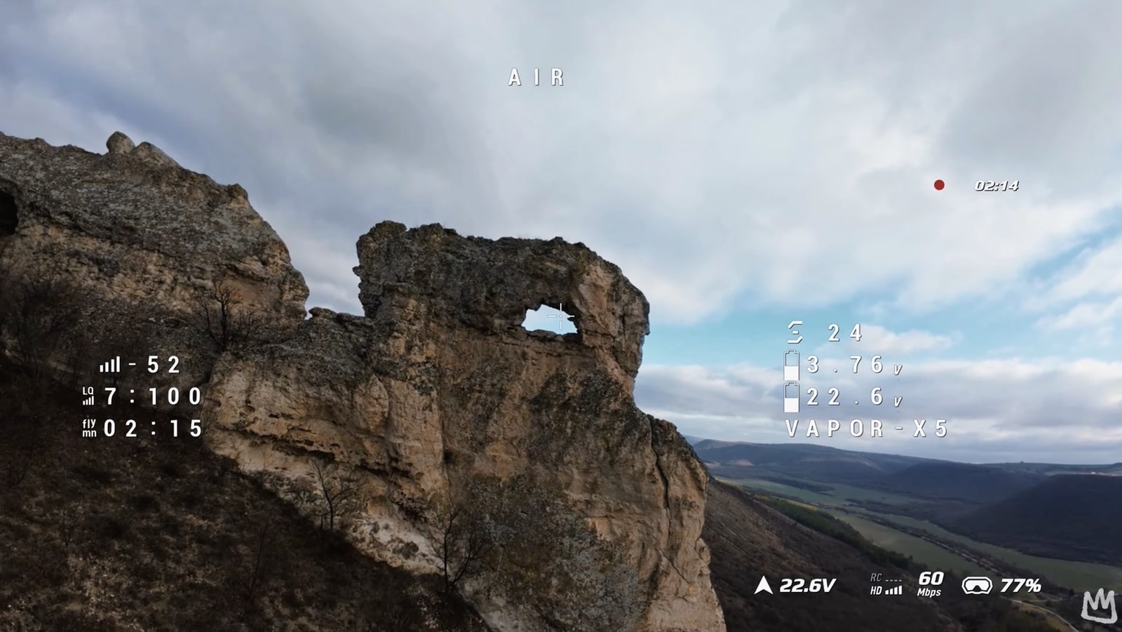 FPV goggles view above a rugged sea cliff with O4 telemetry across the frame.