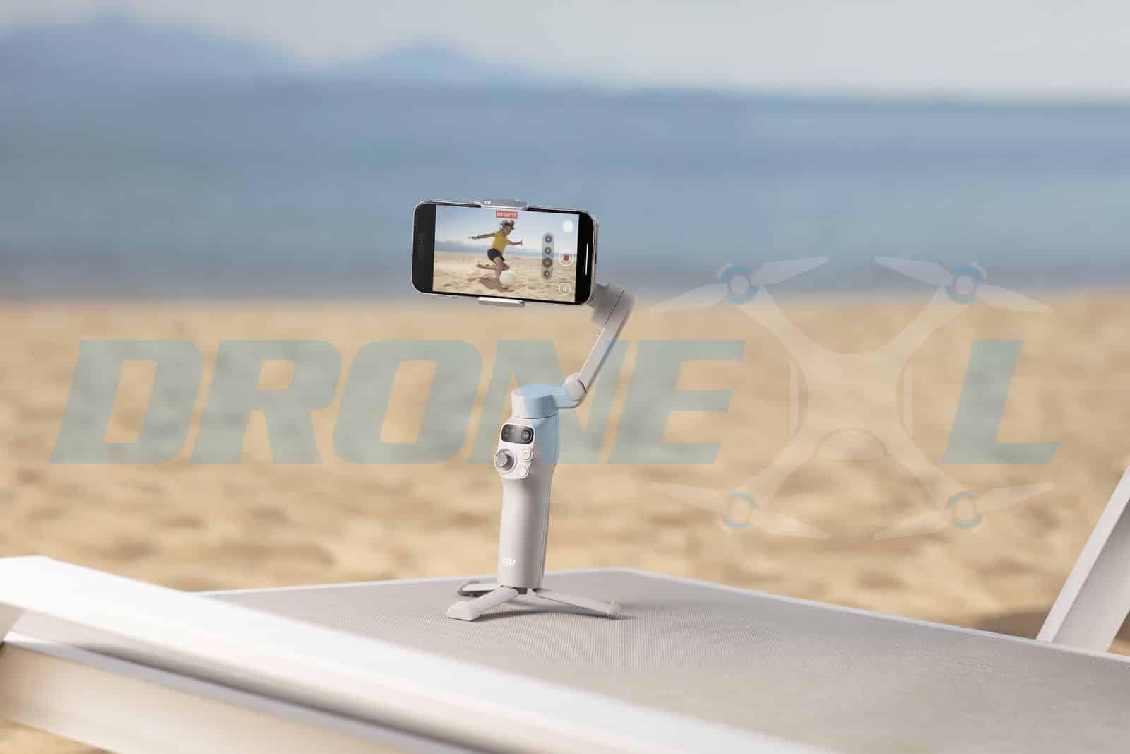 The white gimbal stands on its built-in tripod feet on a sunlit beach deck.