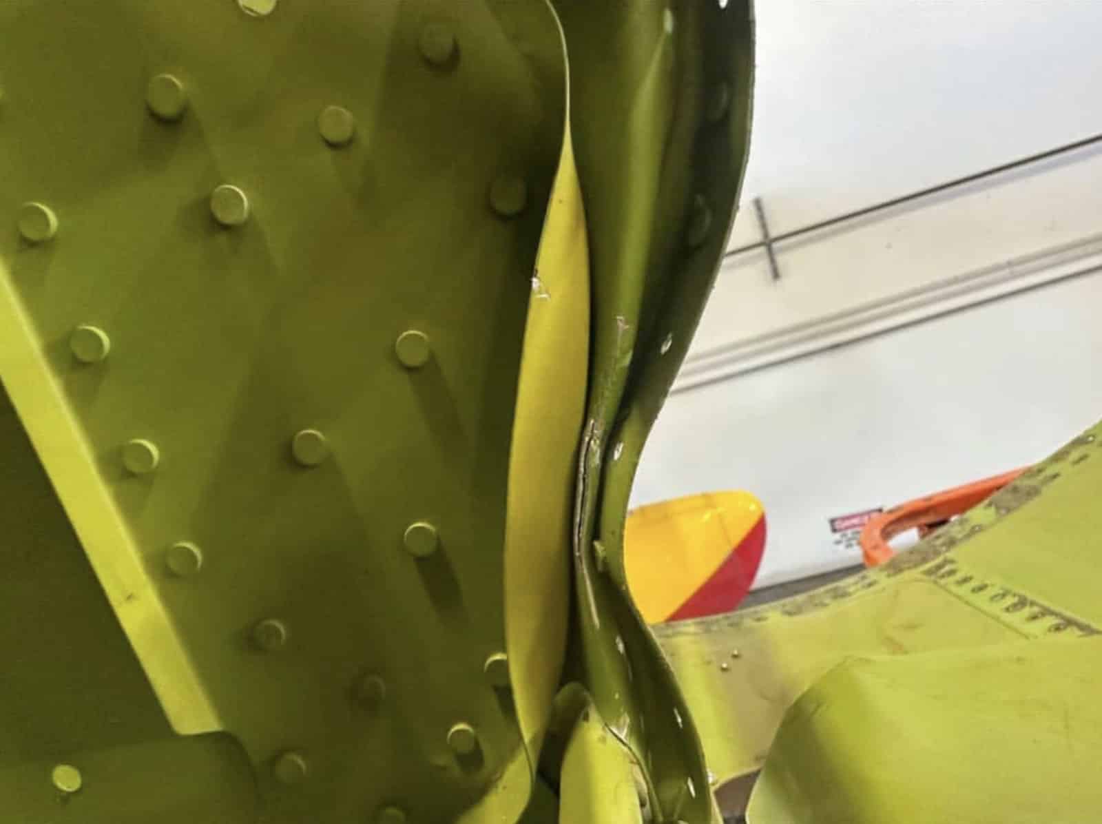 Close-up of a buckled green internal rib deformed by the impact.
