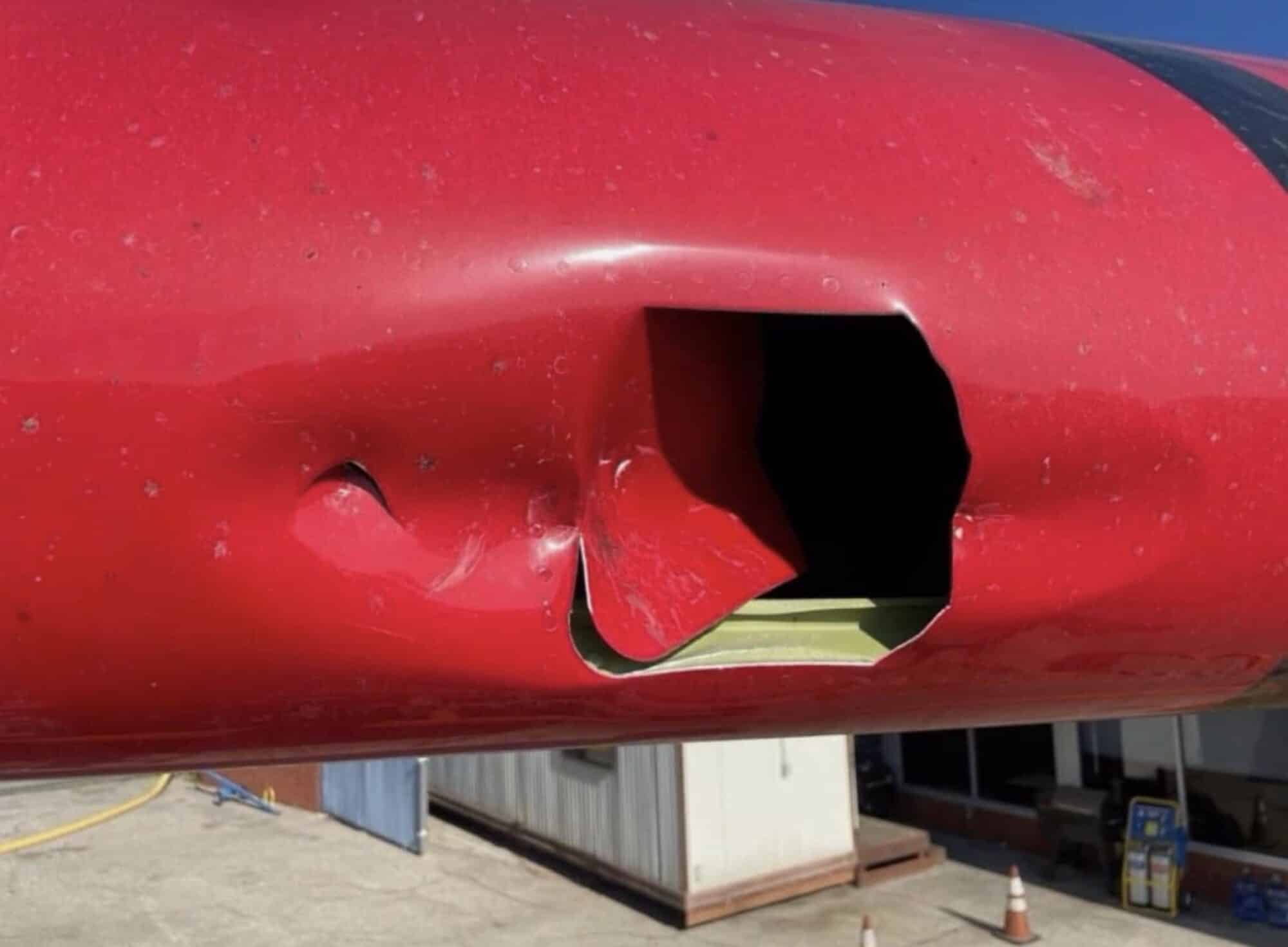 Torn hole punched through the red underside of the firefighting aircraft wing.