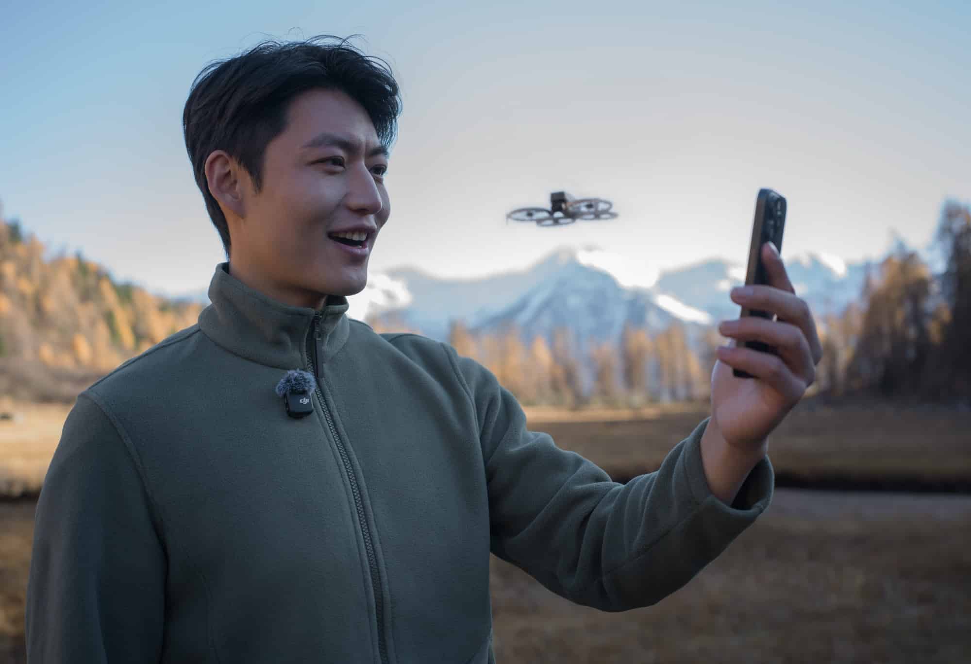 Man wearing a DJI Mic Mini on his collar filming with a phone.