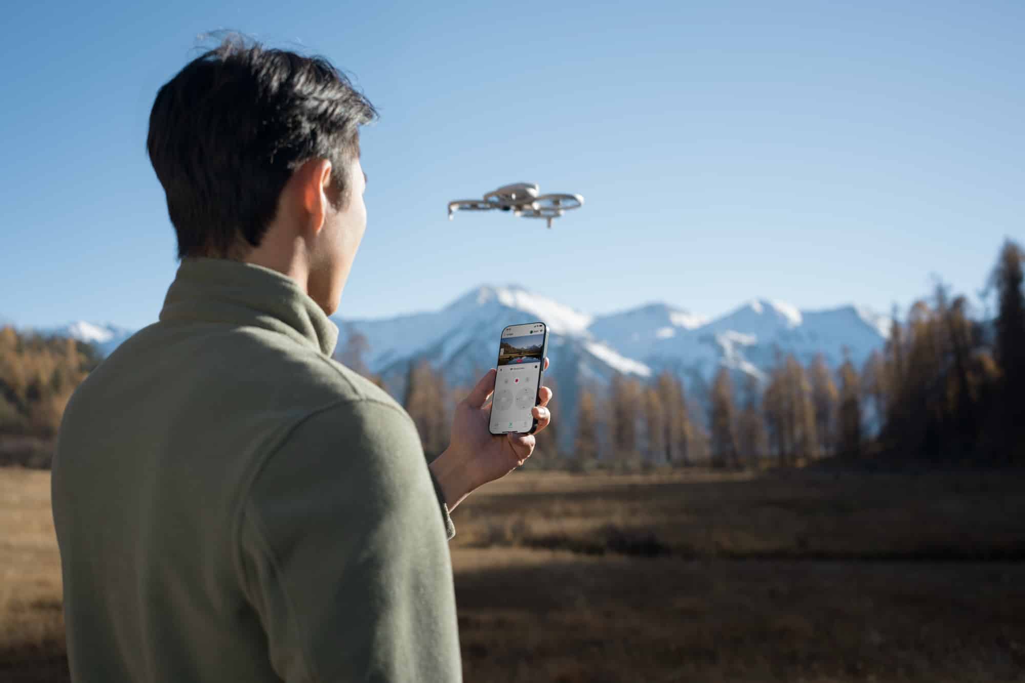 Pilot holding a smartphone in vertical mode with the Flip hovering ahead.