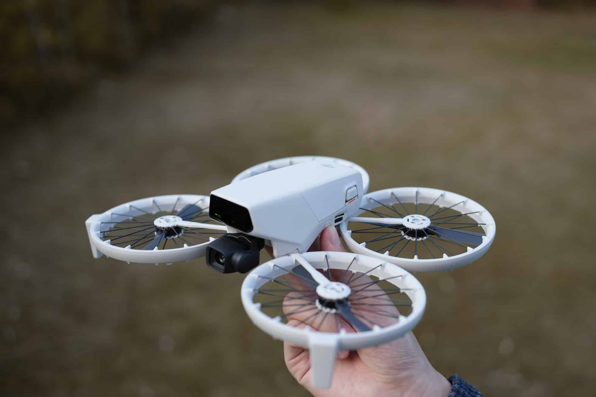 Hand holding the DJI Flip with its full-coverage propeller guards deployed outdoors.