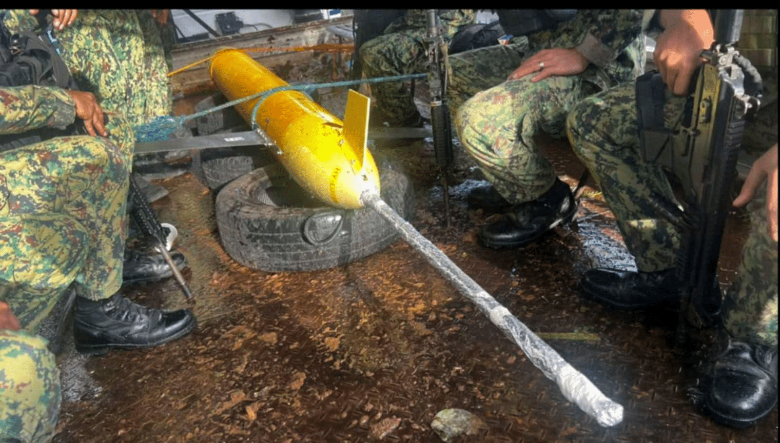 Philippine soldiers guarding a yellow HY-119 underwater drone resting on a tire.