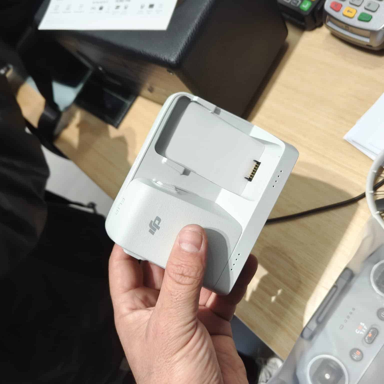 Hand holding the two-bay charging hub with its contact pins facing up.