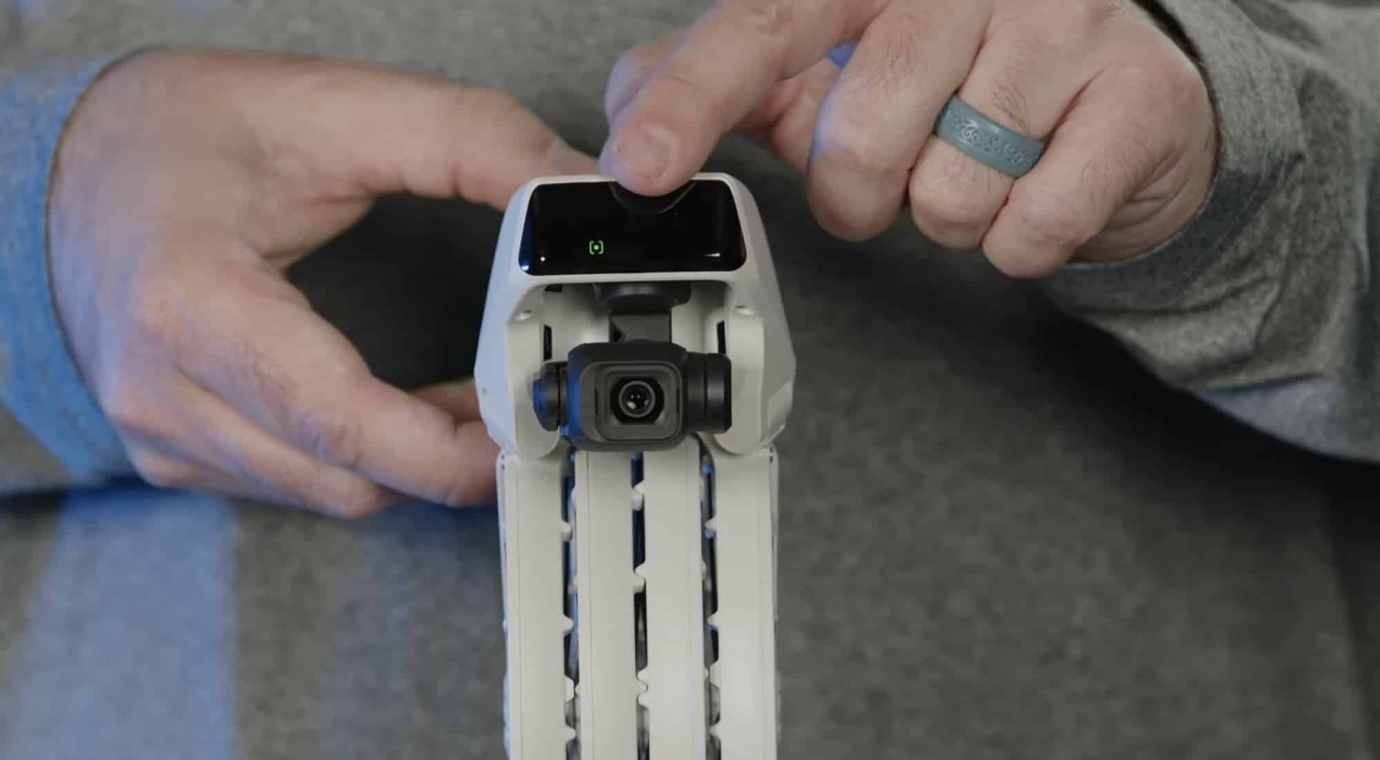 Hands folding the propeller cages of the DJI Flip against a gray background.